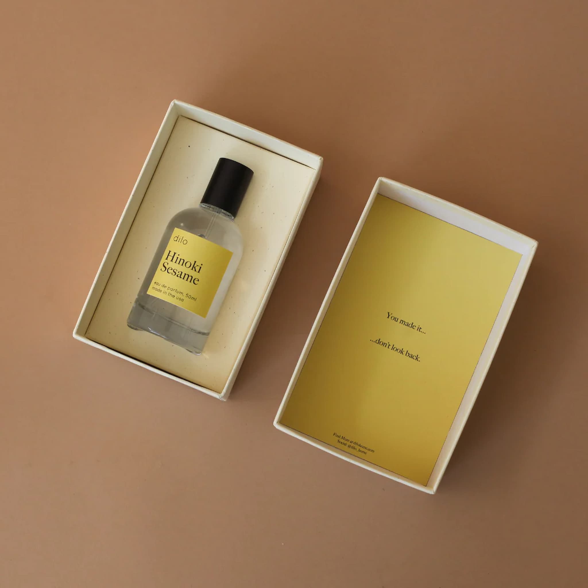 Bottle of Hinoki Sesame perfume in an open box on a brown background