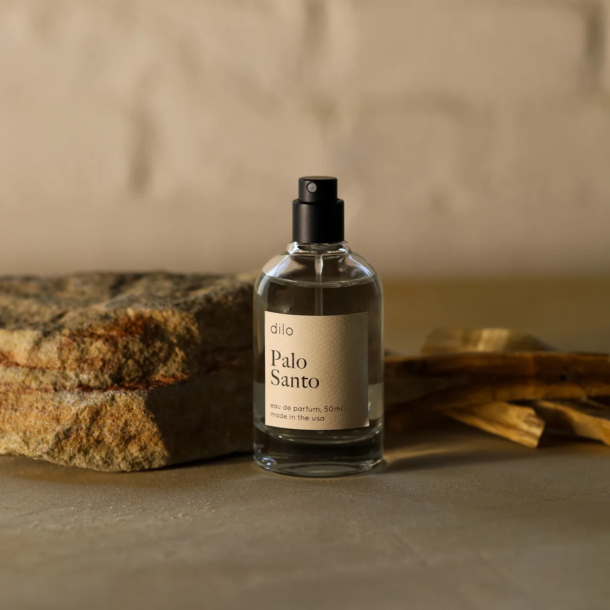 Glass bottle of Dilo Palo Santo perfume with a label on a textured surface.