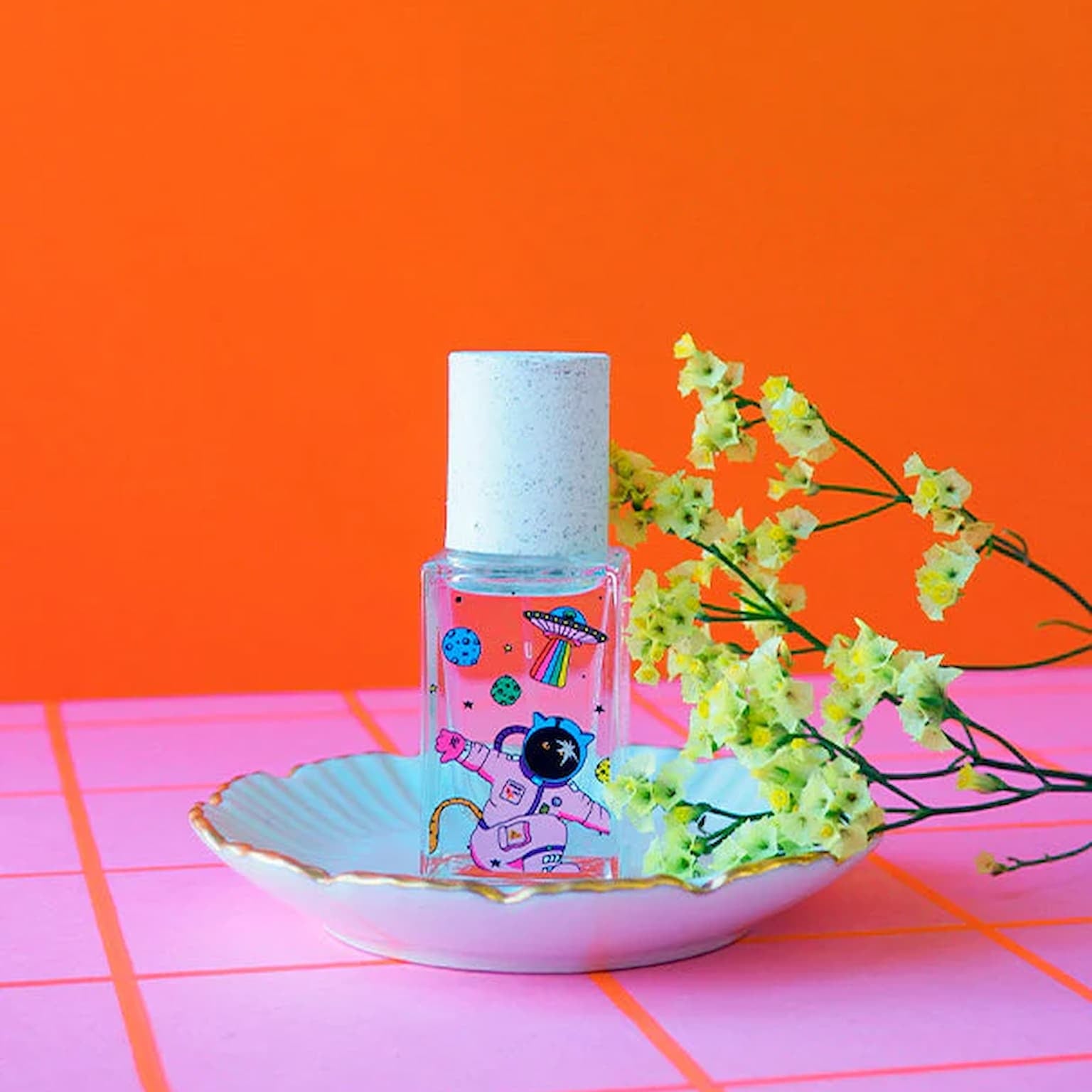 Bottle of perfume with a color design on an orange and pink background.