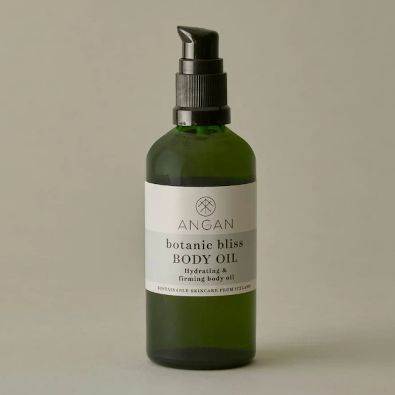 A dark green glass pump bottle of ANGAN Botanic Bliss Body Oil with a black pump dispenser and a white label, set against a solid warm gray background.