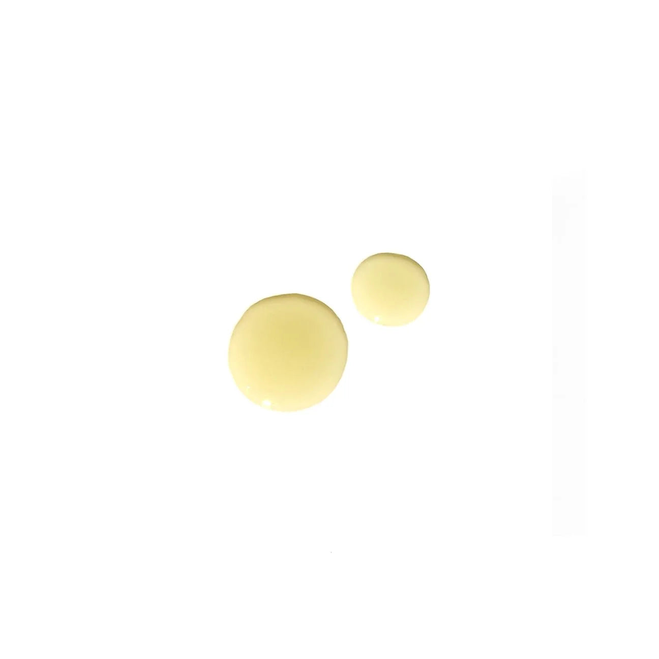 Two yellow spherical dots of Angan body oil on a white background