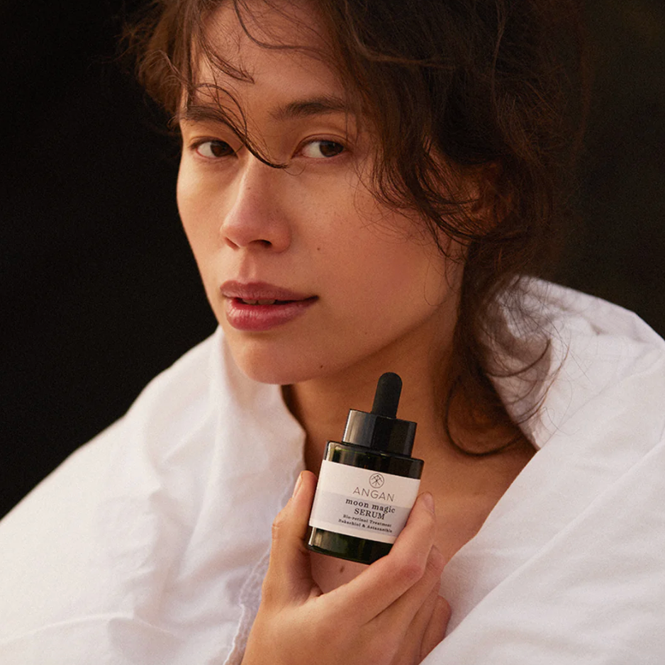 Woman holding a skincare product bottle with a dark background