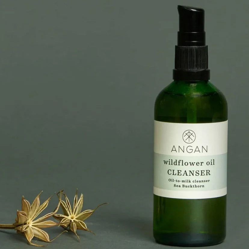 Green bottle of Angan wildflower oil cleanser with a black pump on a gray background.