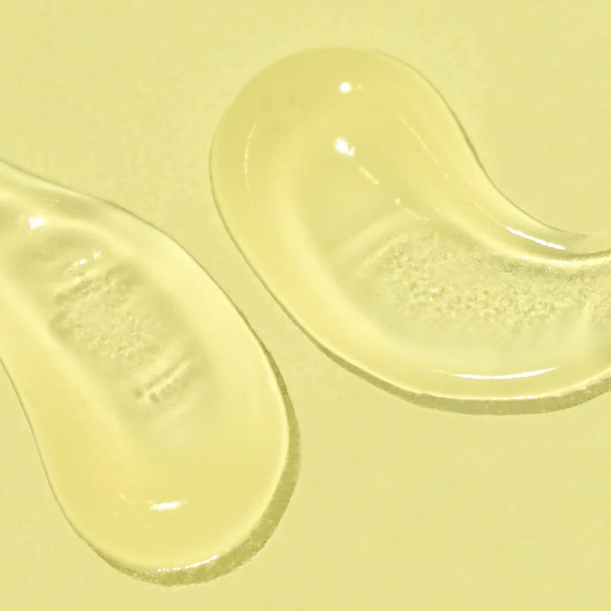 Two swipes of a clear gel SPF on a pale yellow background.