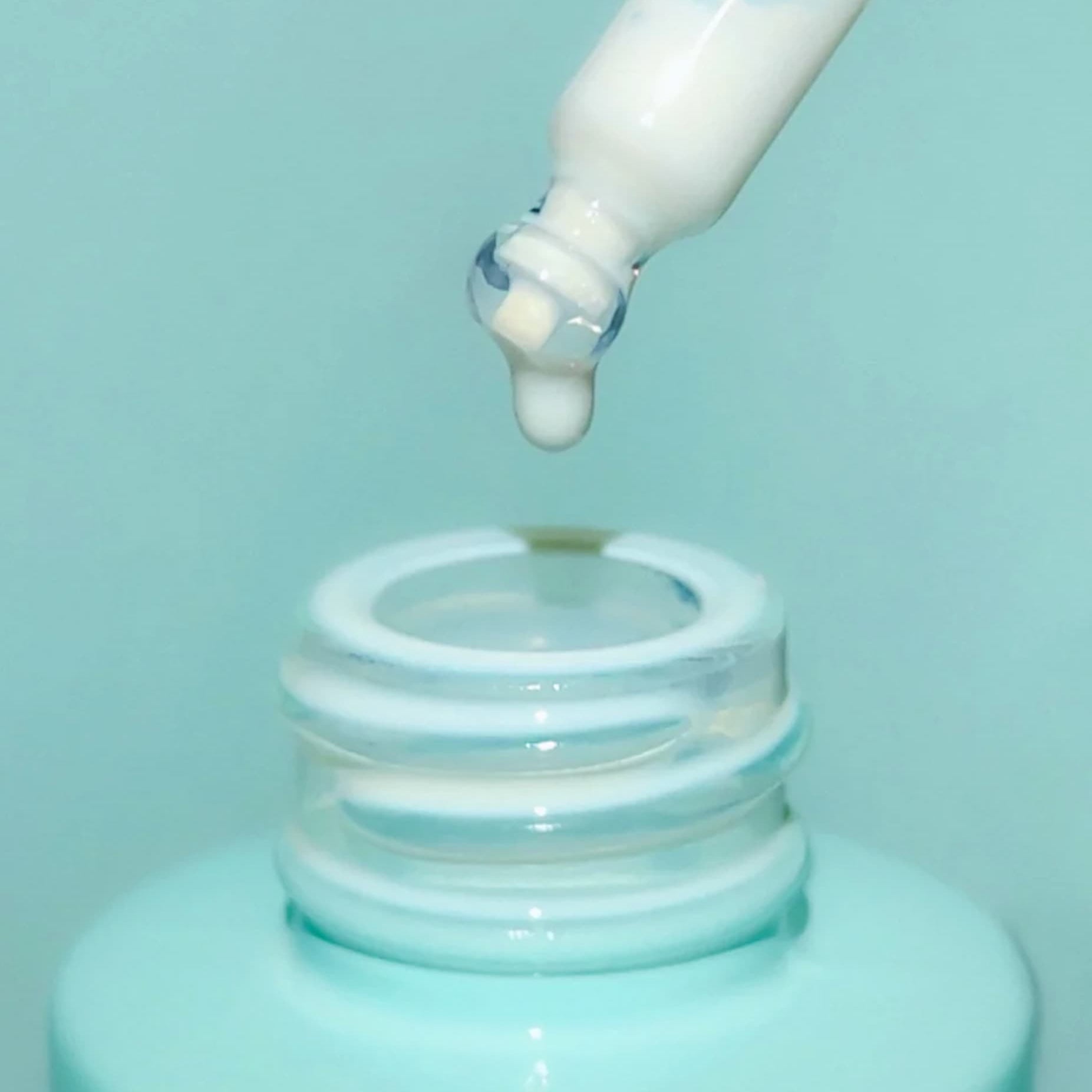 An open bottle of sunscreen serum on a blue background.