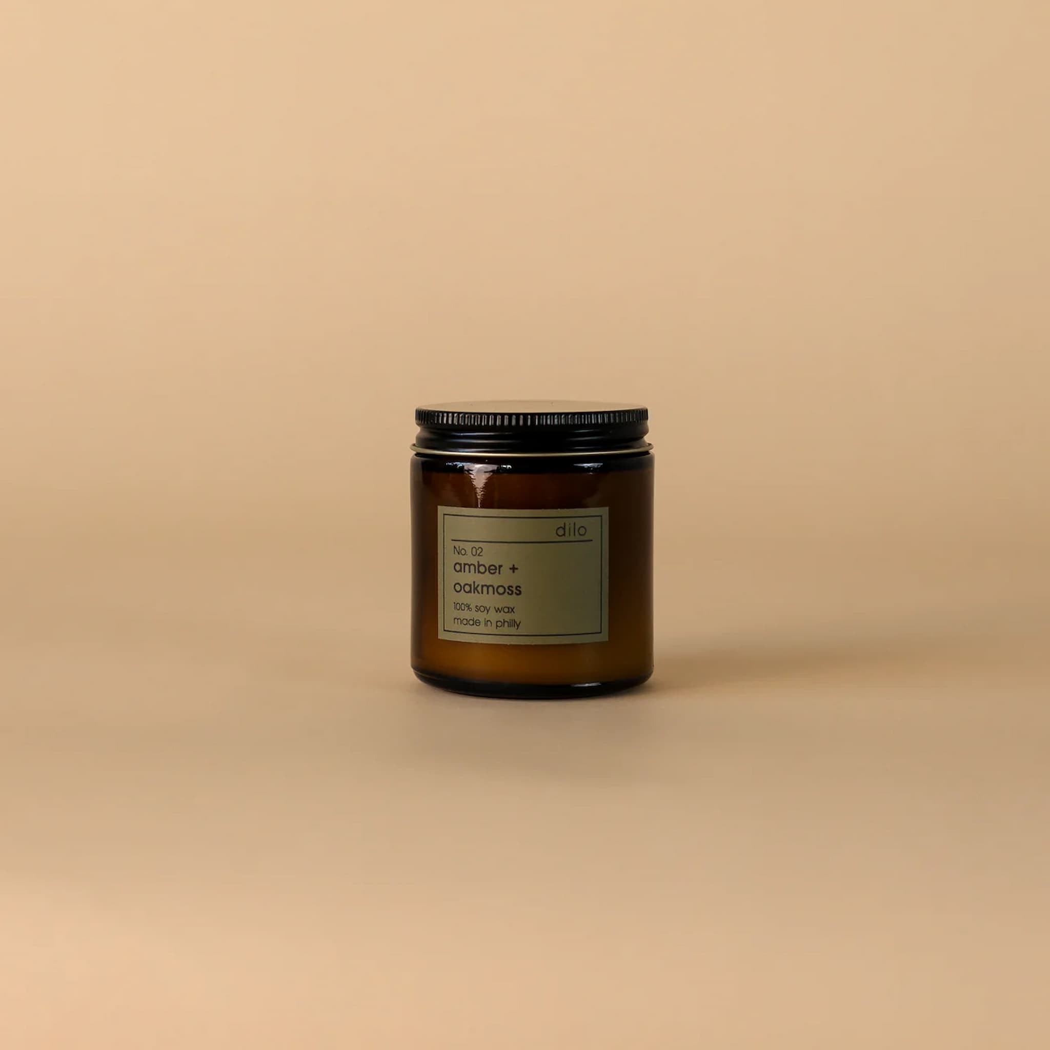 Candle jar in amber glass with a label on a beige background