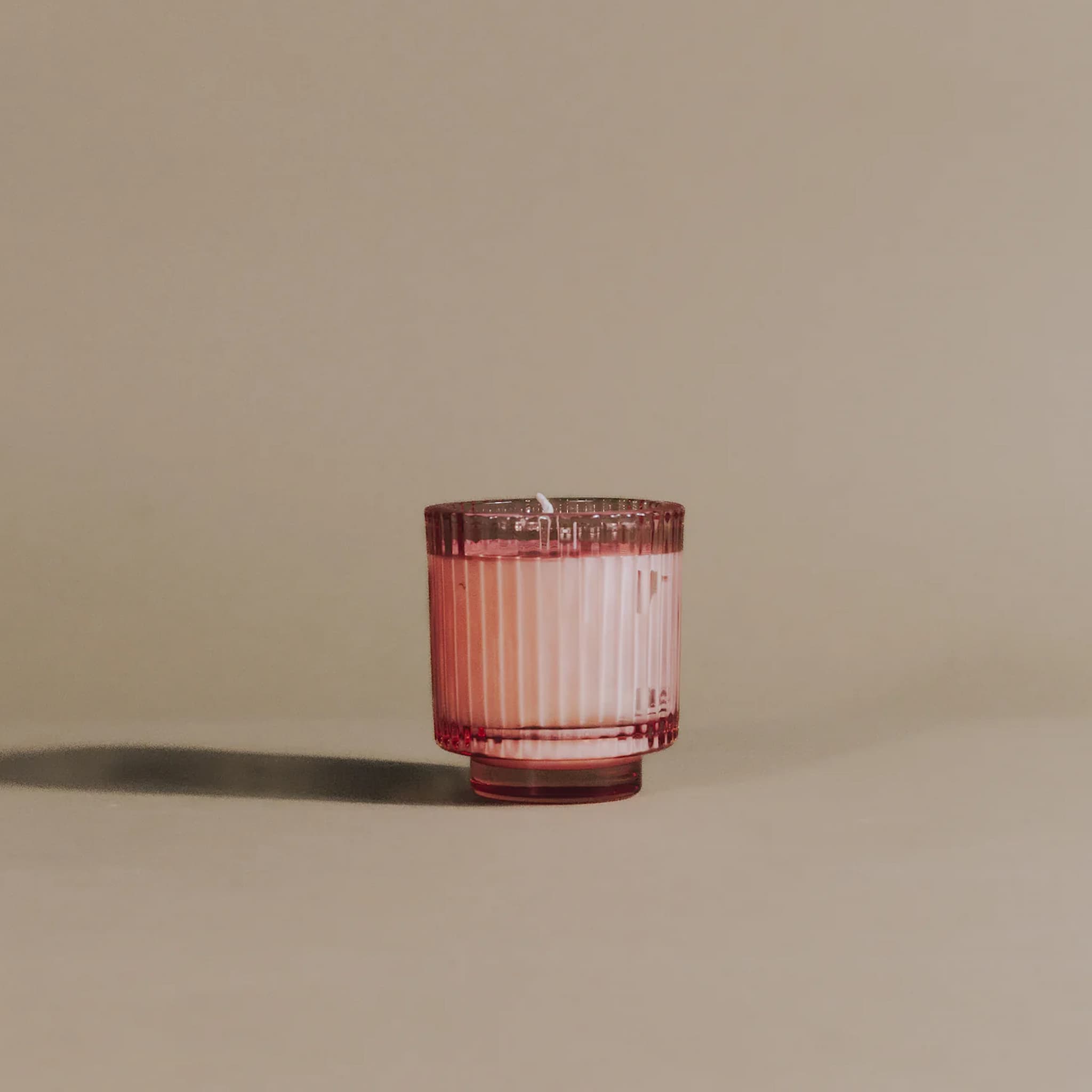 Pink glass candle holder on a beige background