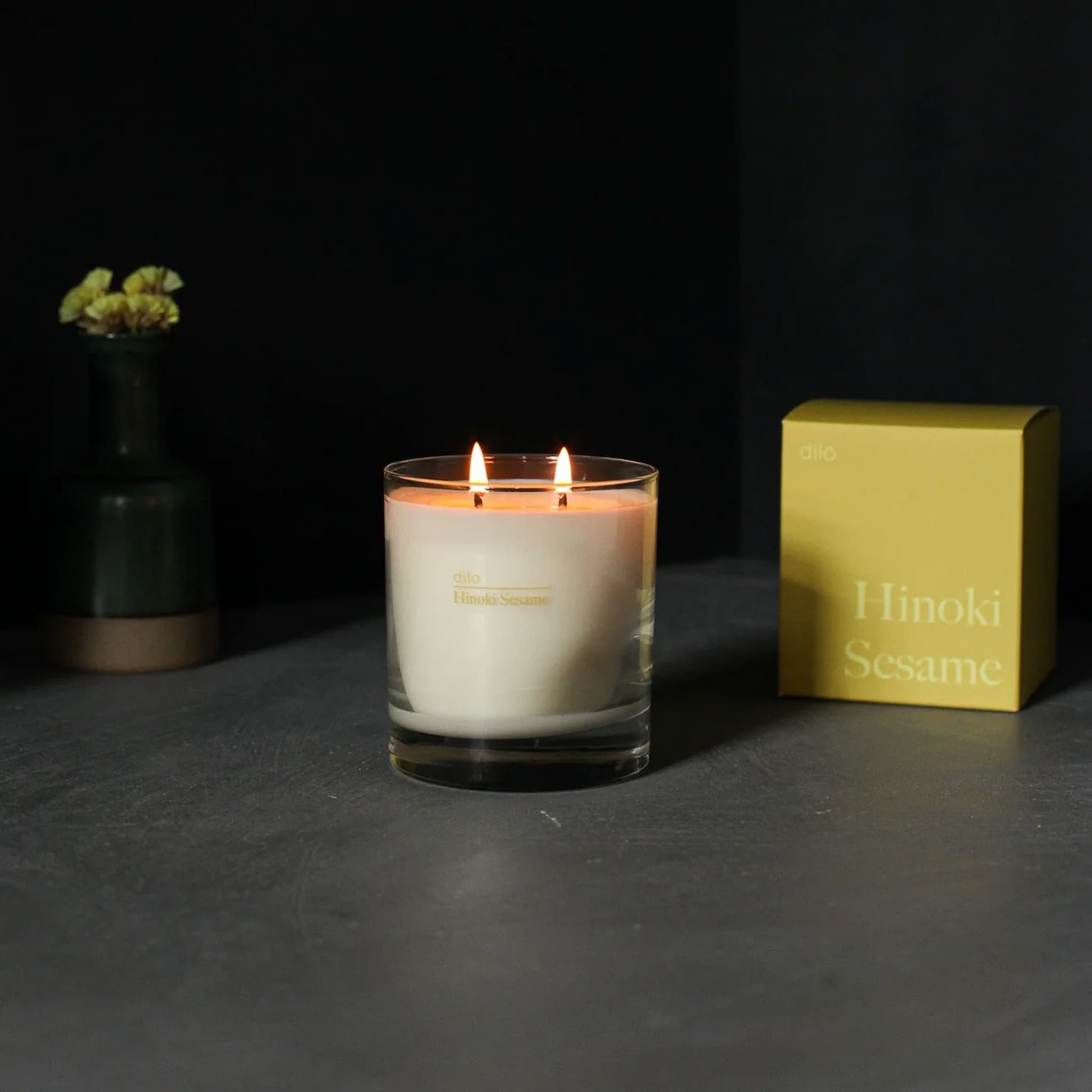 Dilo candle with a yellow box labeled 'Hinoki Sesame' on a dark surface