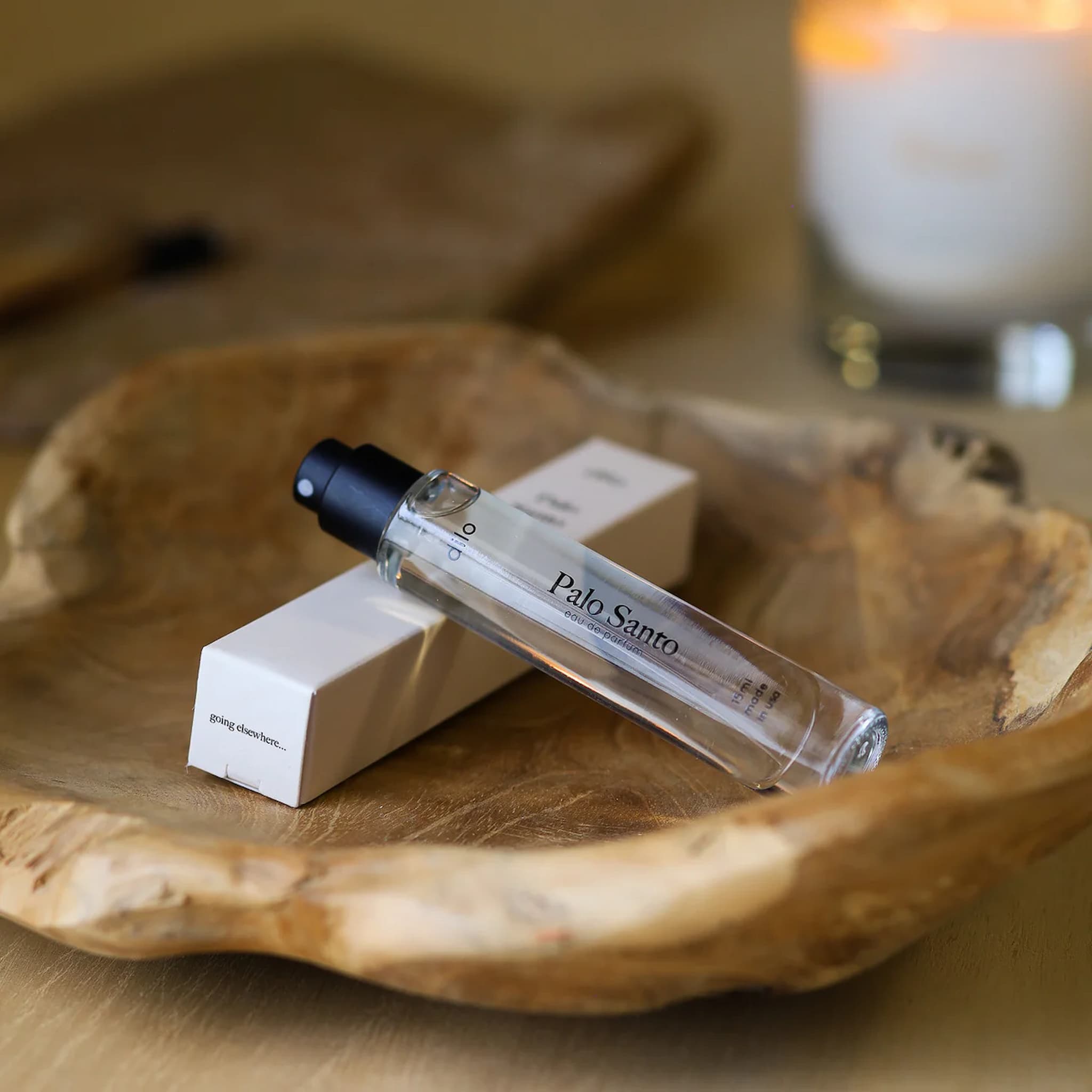 Dilo Palo Santo travel size perfume bottle on a wooden surface with a blurred background