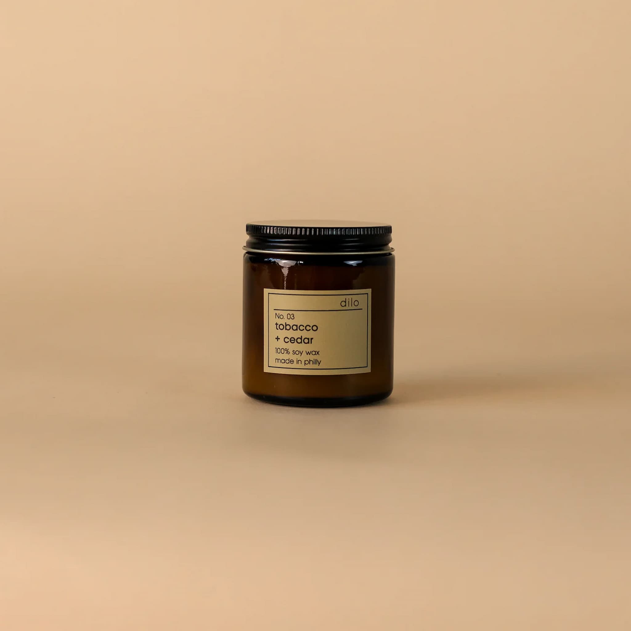 Candle jar in amber glass with a label on a beige background