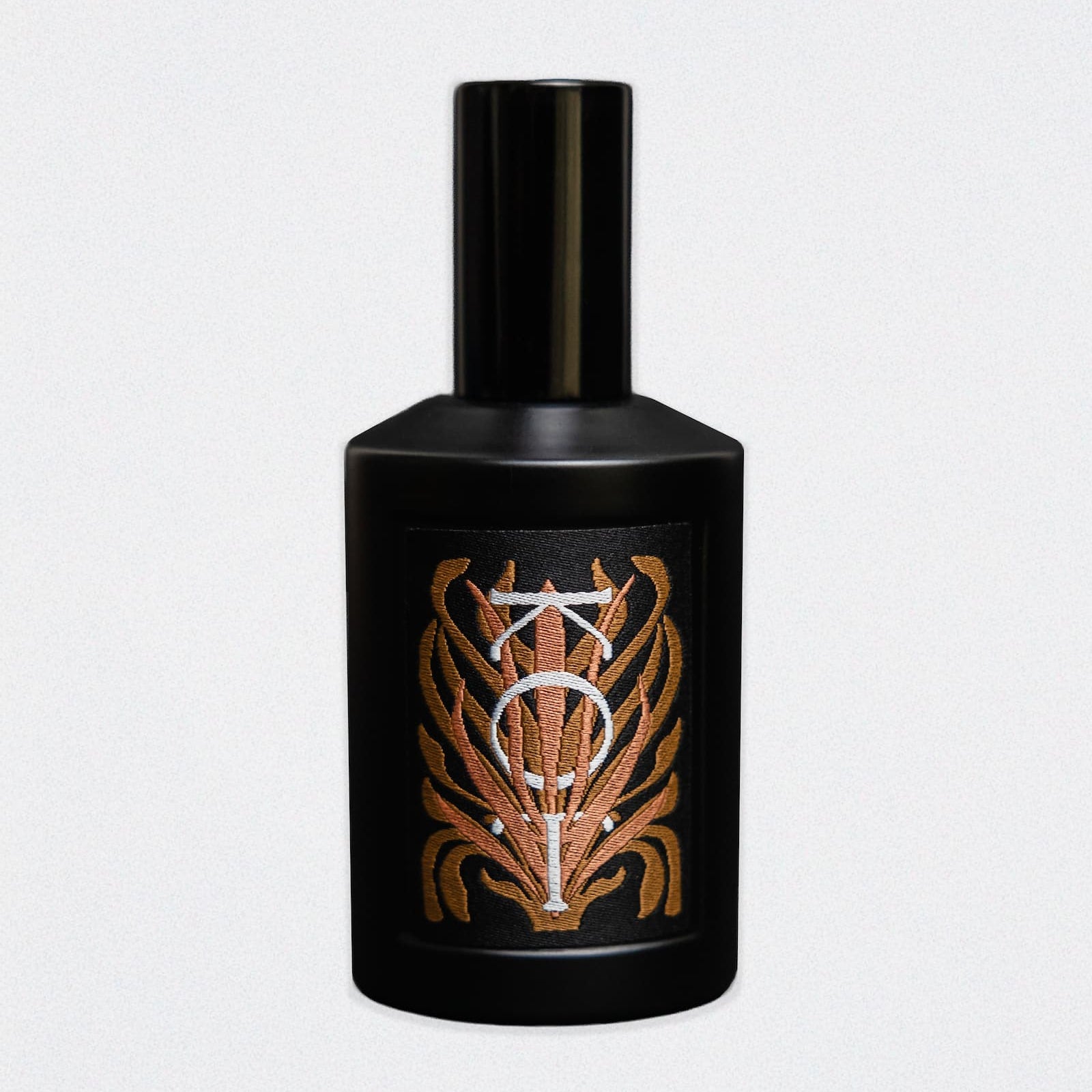 A black cylindrical bottle of Fischersund KOT fragrance with a matching black cap, featuring a front label with a stylized metallic gold and silver emblem, set against a white background.