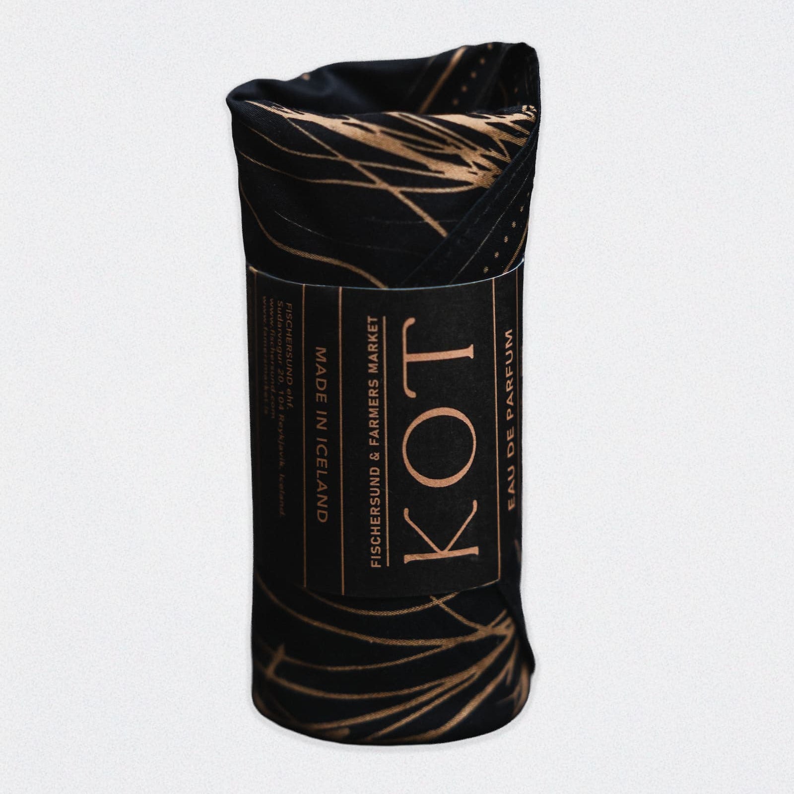 A rolled black bandana with a gold pattern covering a bottle of Fischersund KOT fragrance. The rolled bottle appears on a white background.