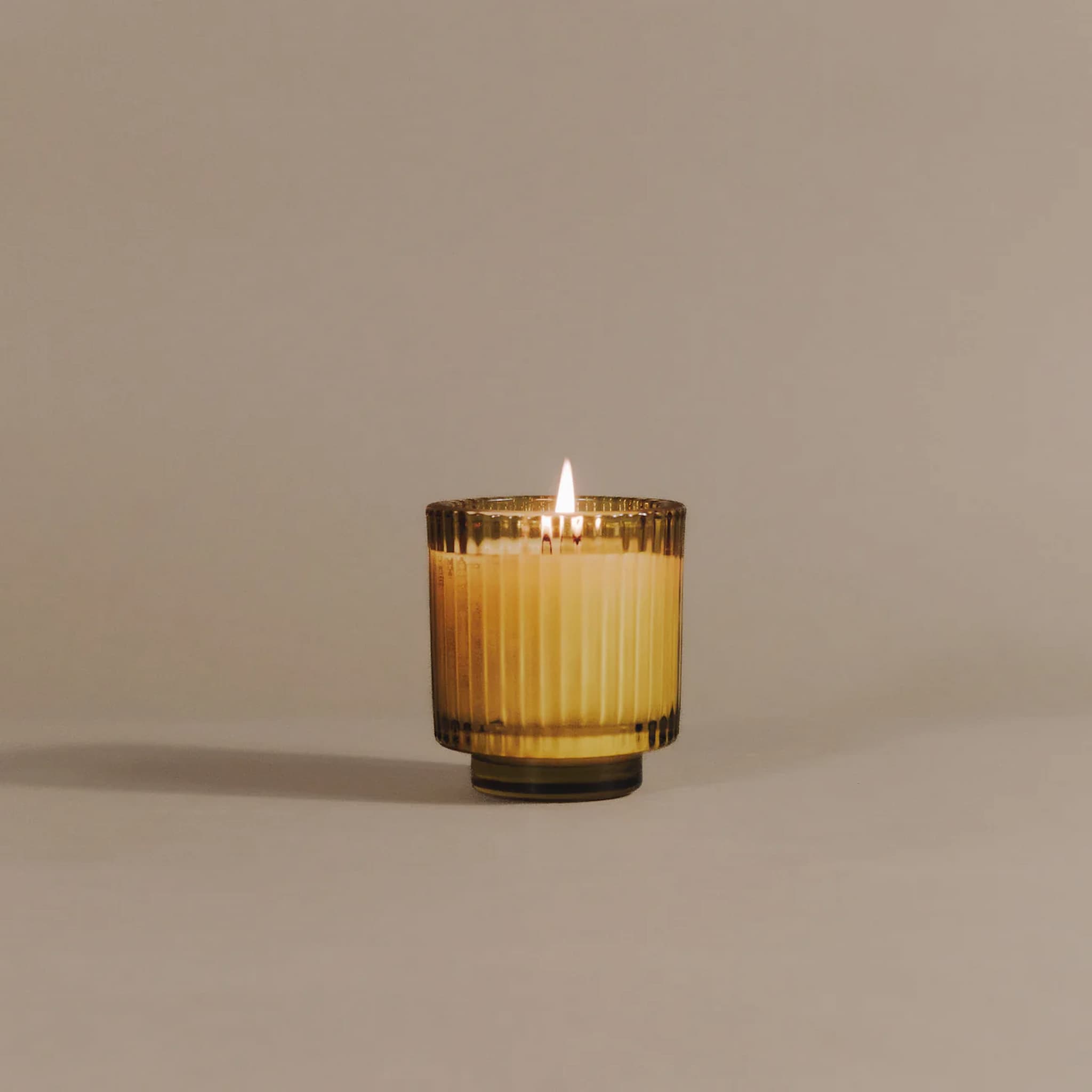 Candle in a glass holder on a beige background