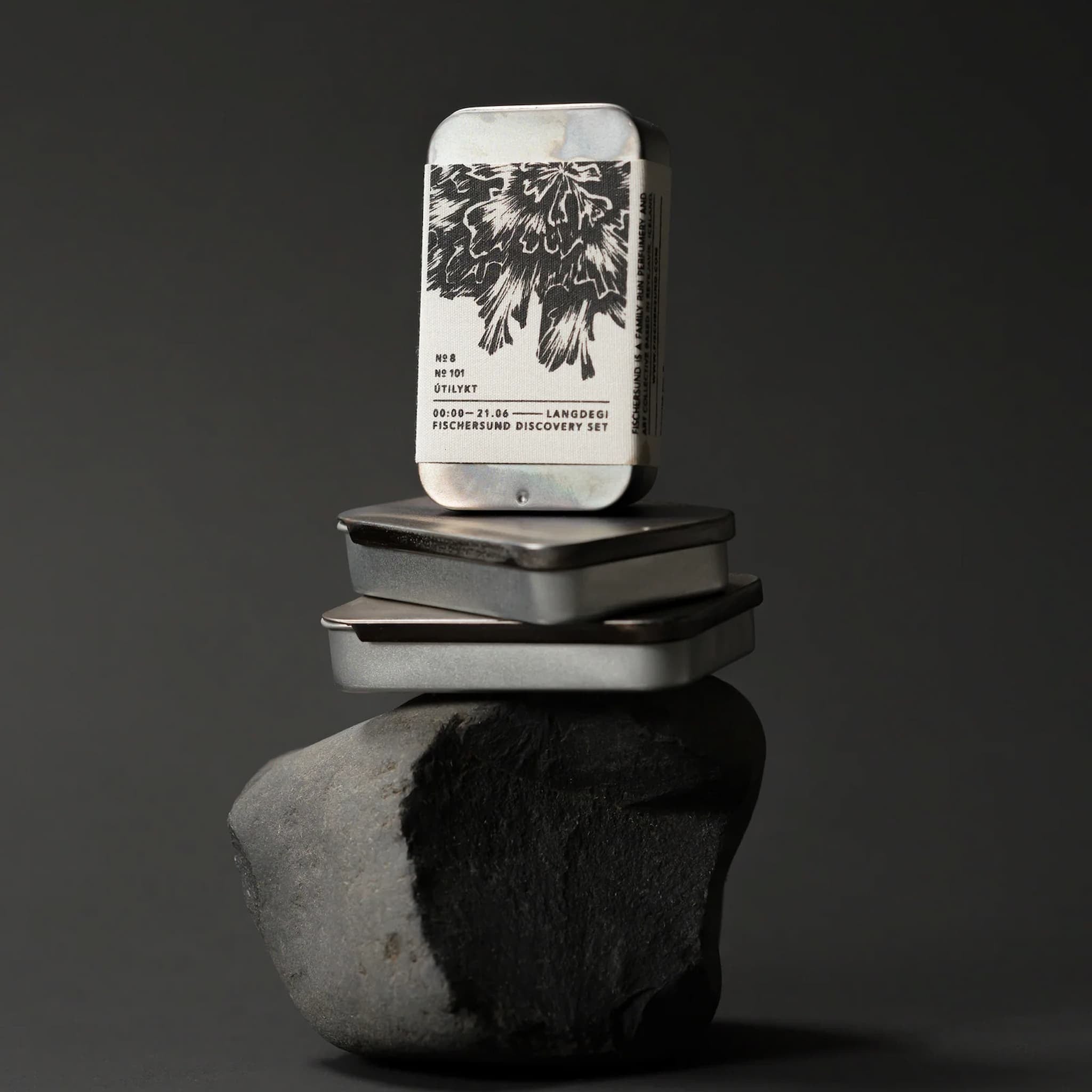 Fischersund Langdegi Light Discovery Set tins stacked on a rock against a dark background