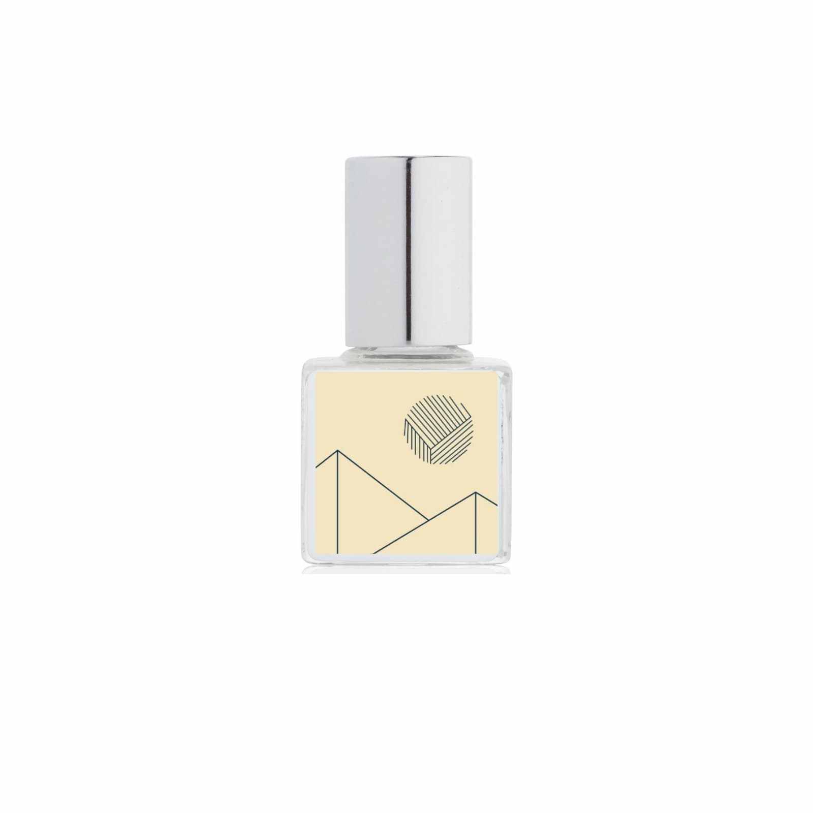 A clear glass bottle of Kelly + Jones Mezcal Blanca perfume oil with a silver cylindrical cap and a pale yellow label featuring a minimalist black geometric line design, centered on a white background.