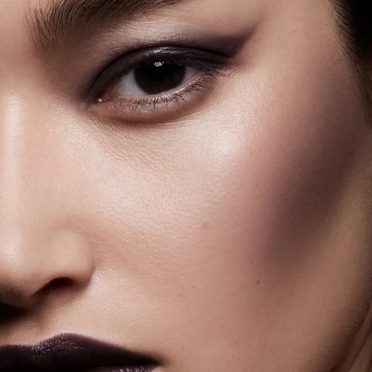 Close-up of a model's face, they are wearing Rituel de Fille Inner Glow Creme Pigment in "Eclipse".