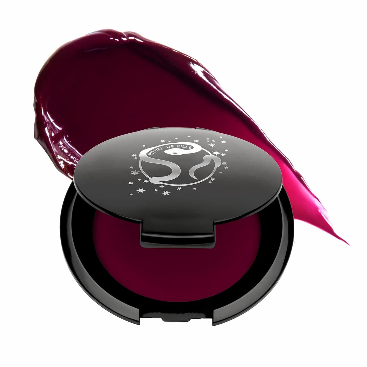 A black compact of Rituel de Fille Inner Glow Pigment Balm in "Glasswing", with a swatch of the product behind it.