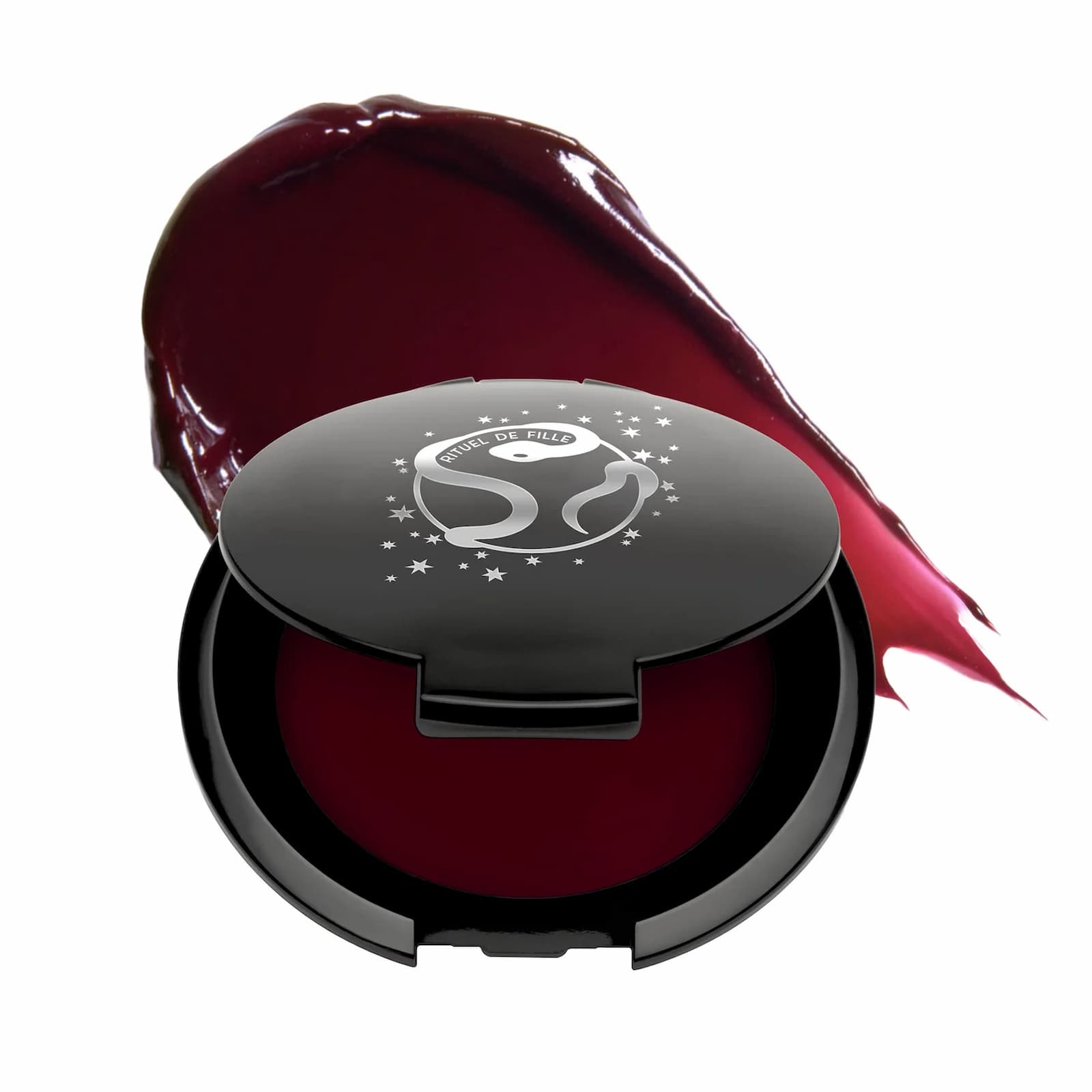 A black makeup compact of Rituel de Fille Inner Glow Pigment Balm in "Weeping Cherry", with a swatch of product behind.