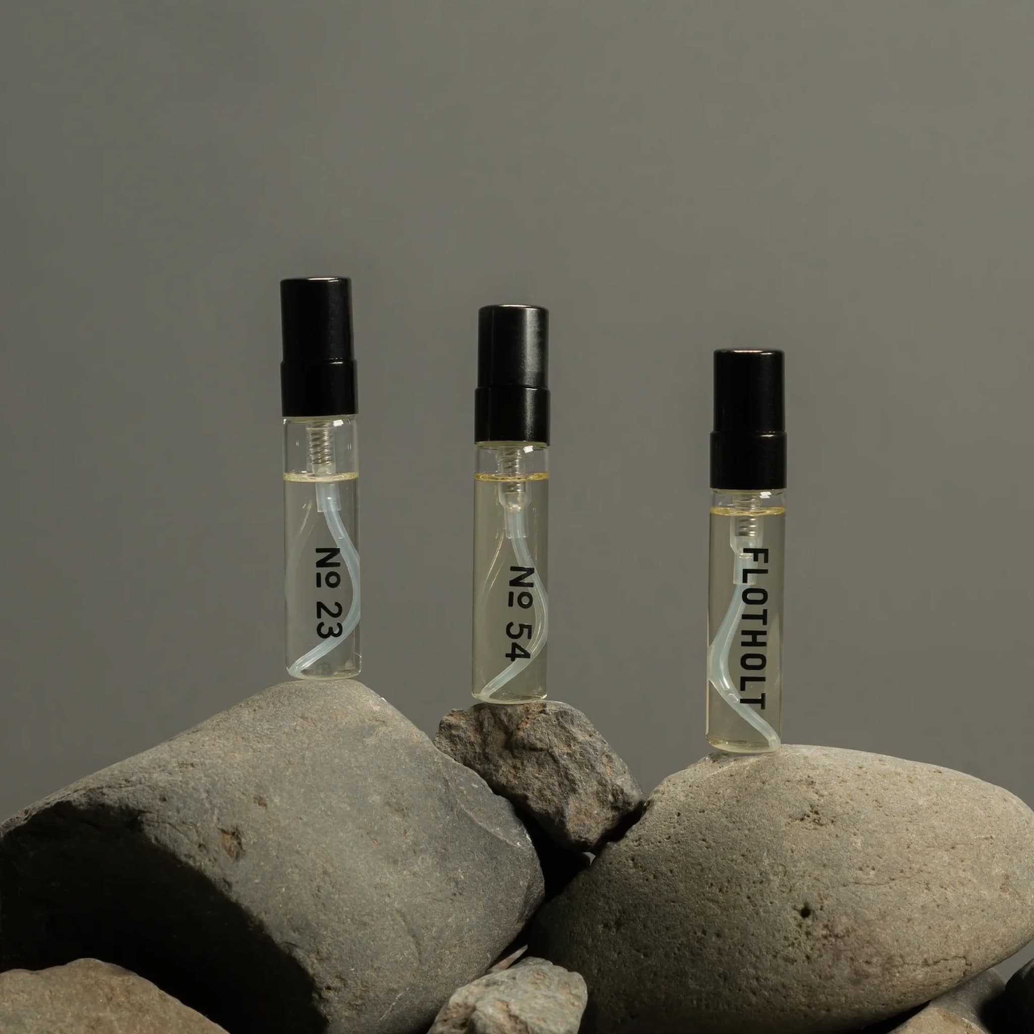 Fischersund fragrance vials labeled 'No 23', 'No 54', and 'FLOTHOLI' on rocks with a gray background