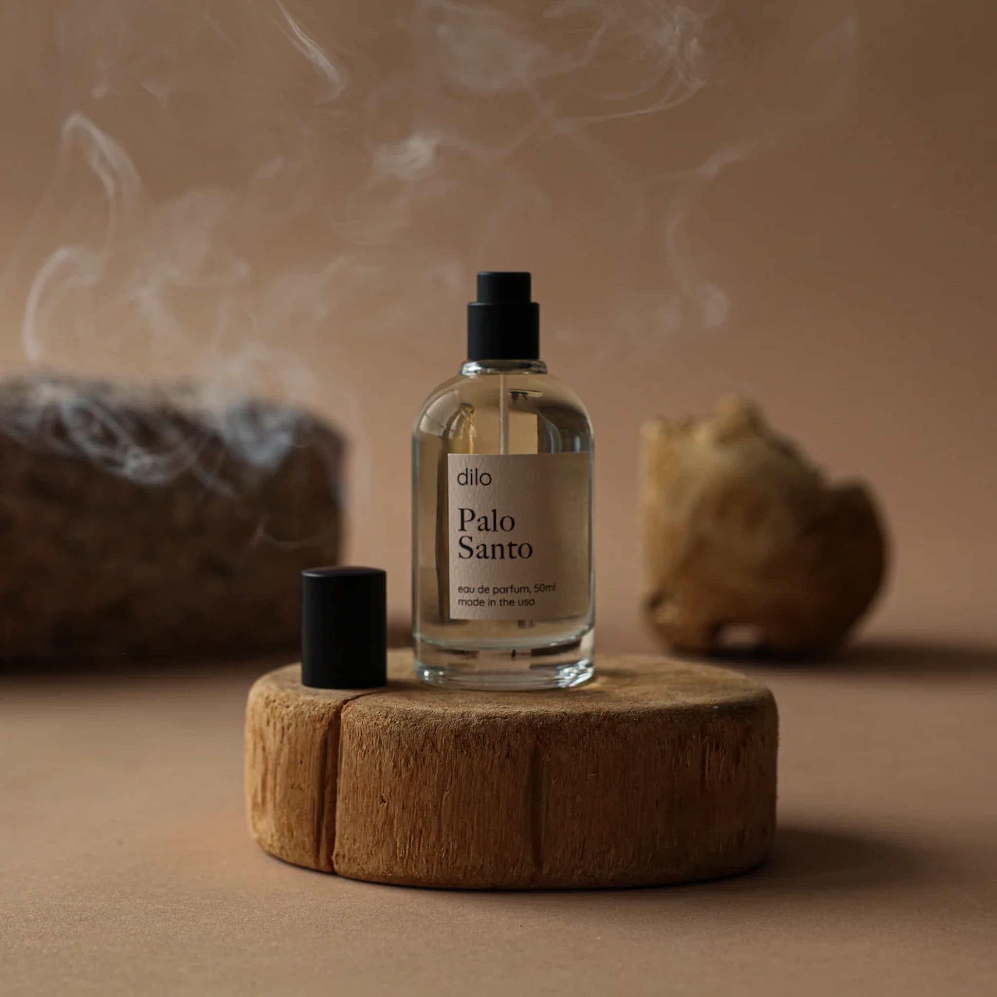 Bottle of Dilo Palo Santo on a wooden platform with smoke in the background