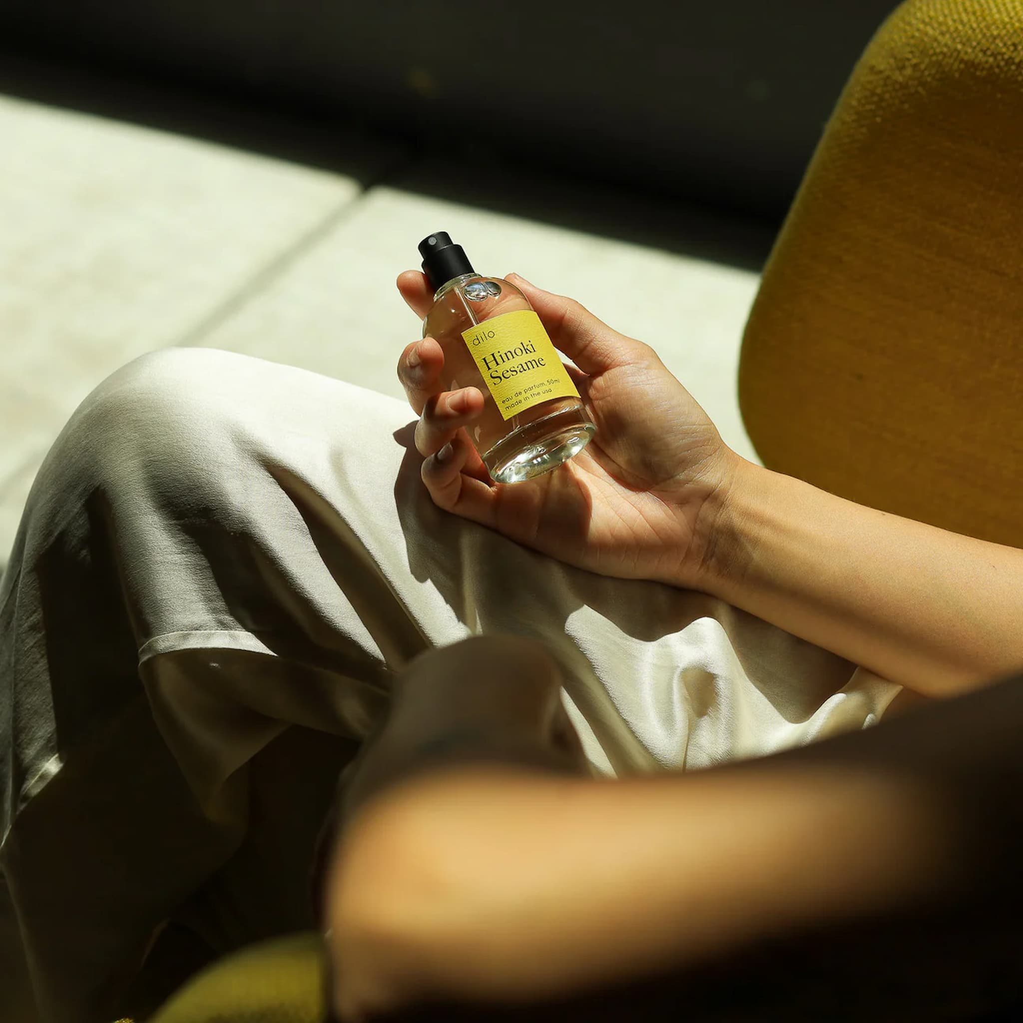 Person holding a bottle of Hinoki Sesame perfume in a casual setting