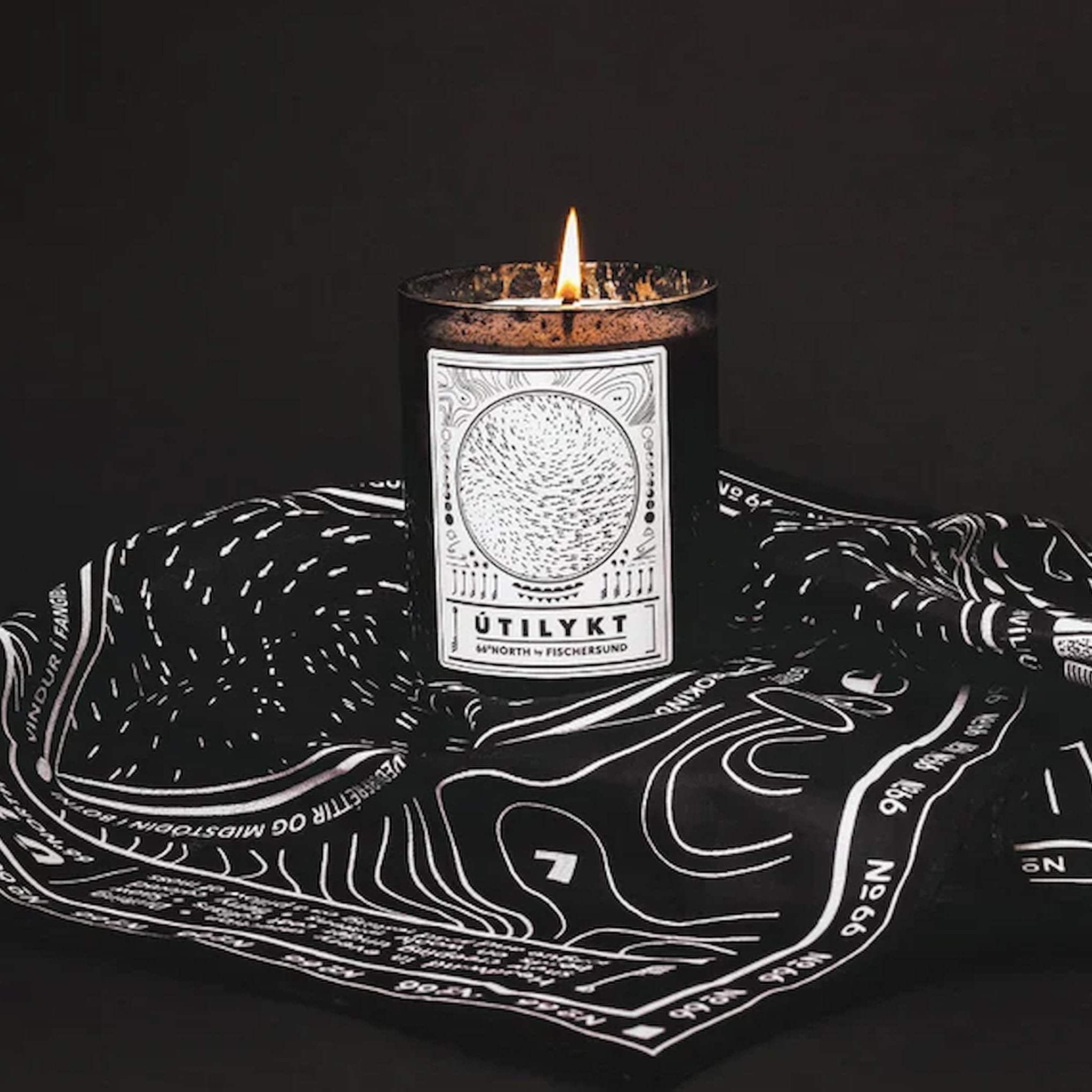Fischersund Utilykt candle with a label on a black and white patterned cloth against a dark background