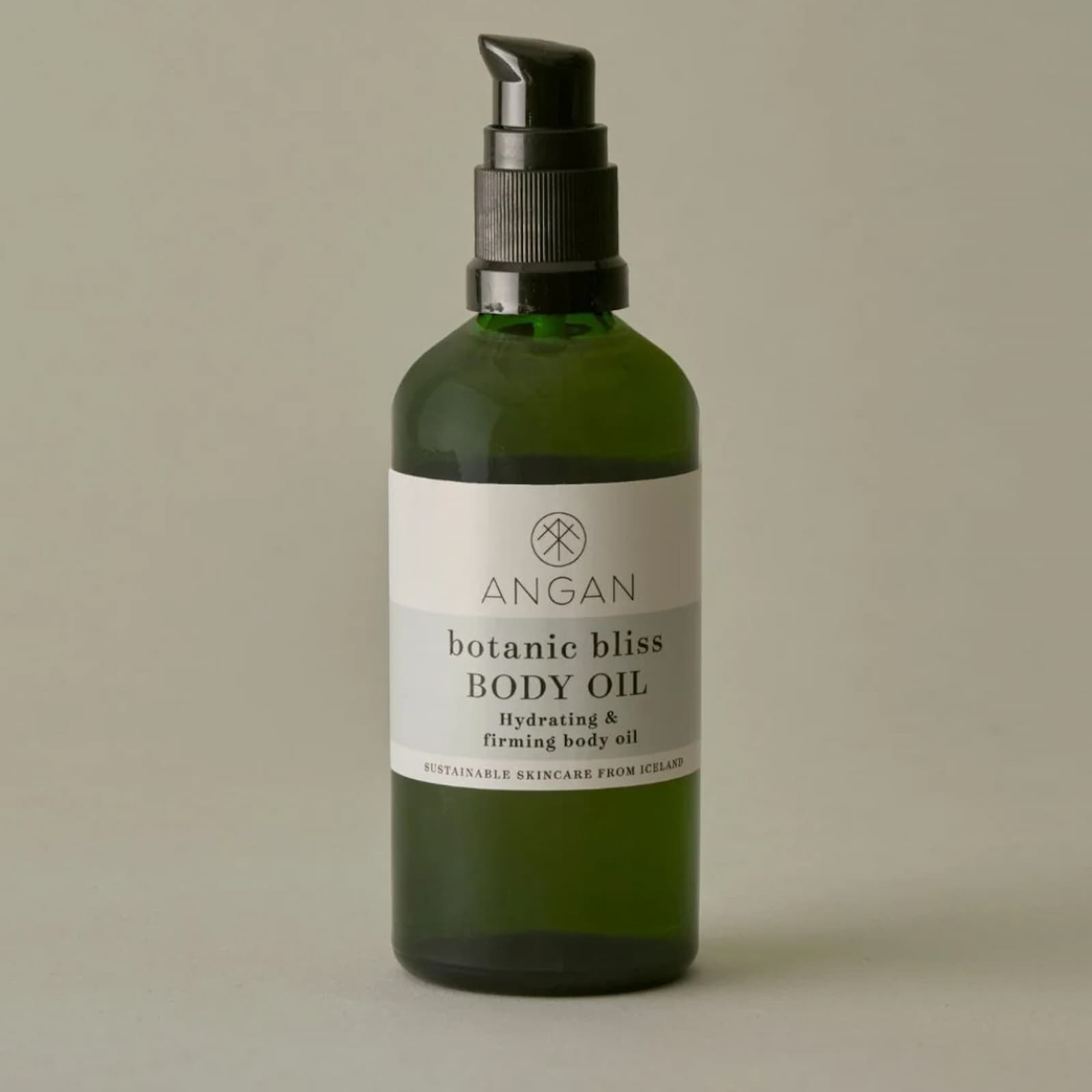 A dark green glass bottle of Angan Westfjords Botanic Bliss Body Oil against a grey-green background.