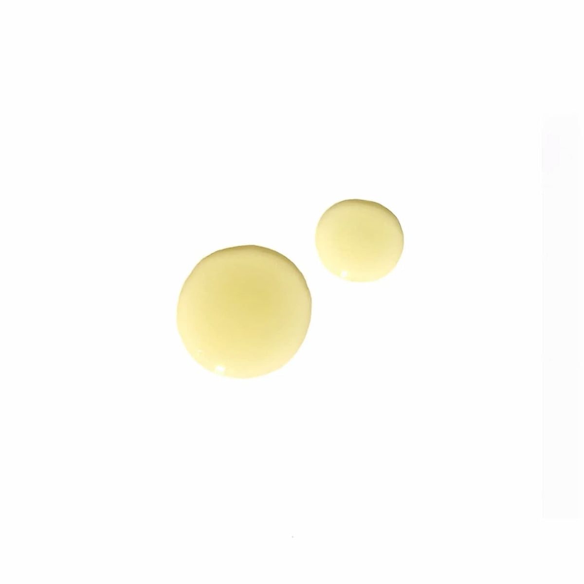 Two yellow drops of Angan Westfjords Botanic Bliss Body Oil against a white background.