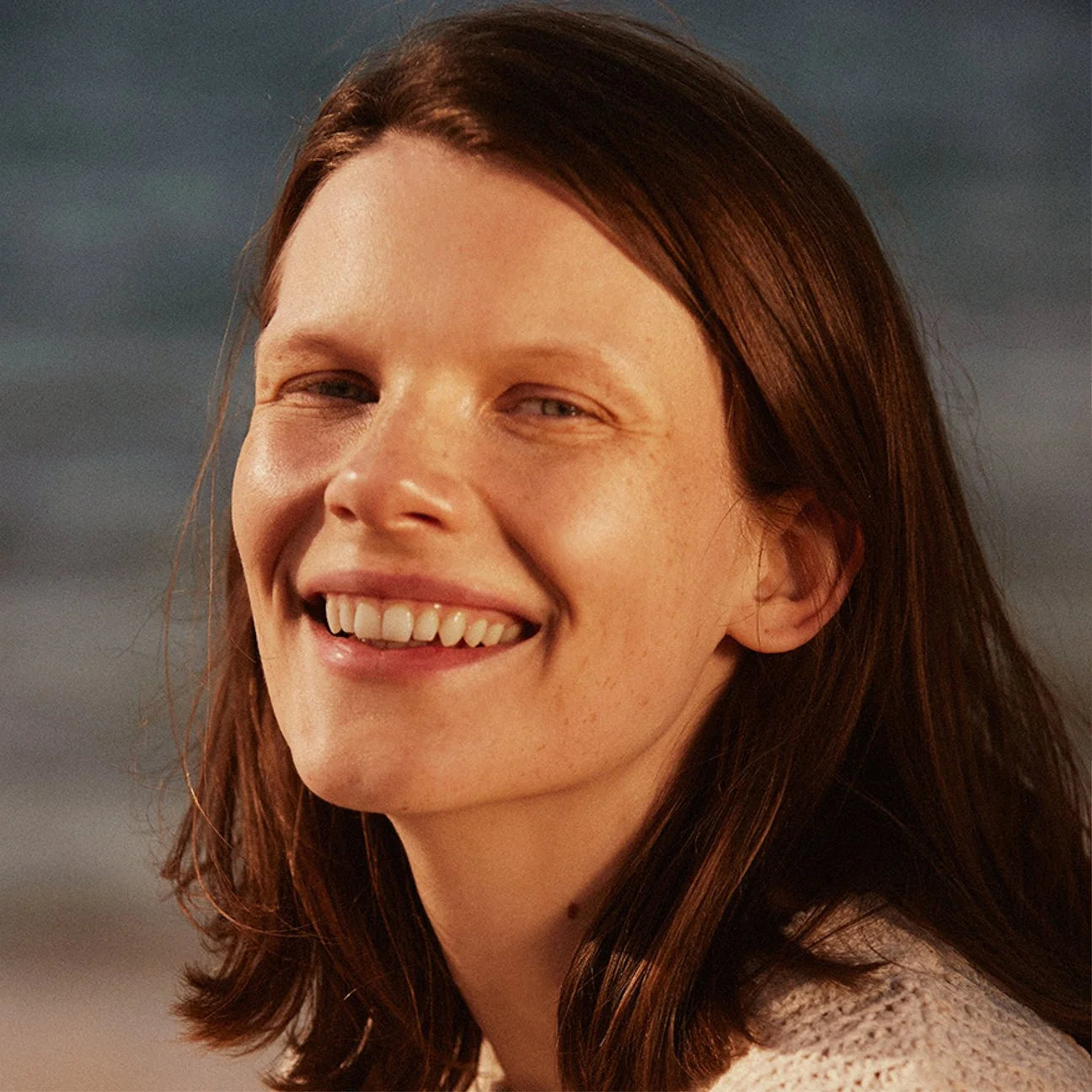 Woman with shoulder-length brown hair smiling outdoors