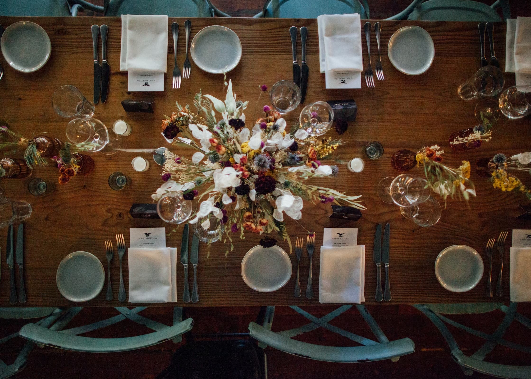 Dining table at the Bird & Bottle Inn in Garrison, NY, set with floral centerpieces, plates, and cutlery for a Hudson Valley wedding.