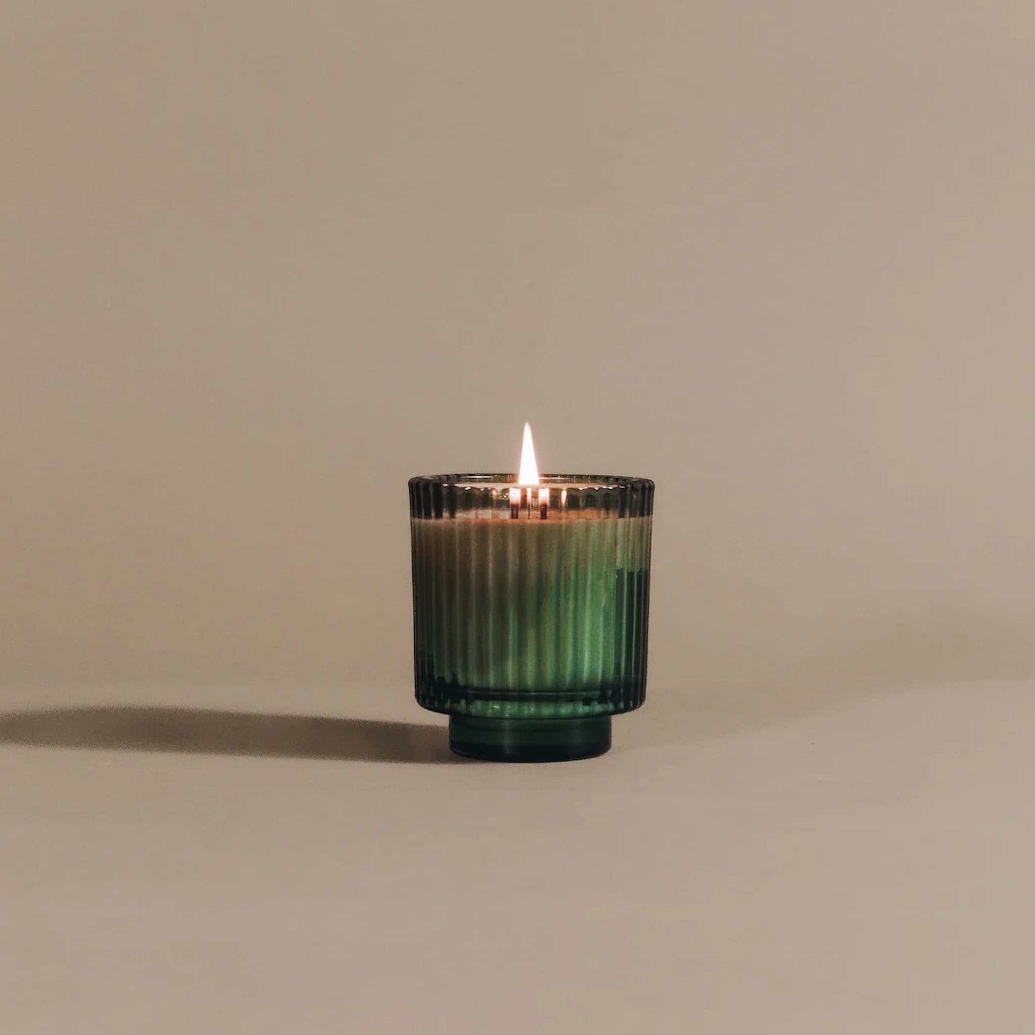 Candle in a green glass holder on a beige background