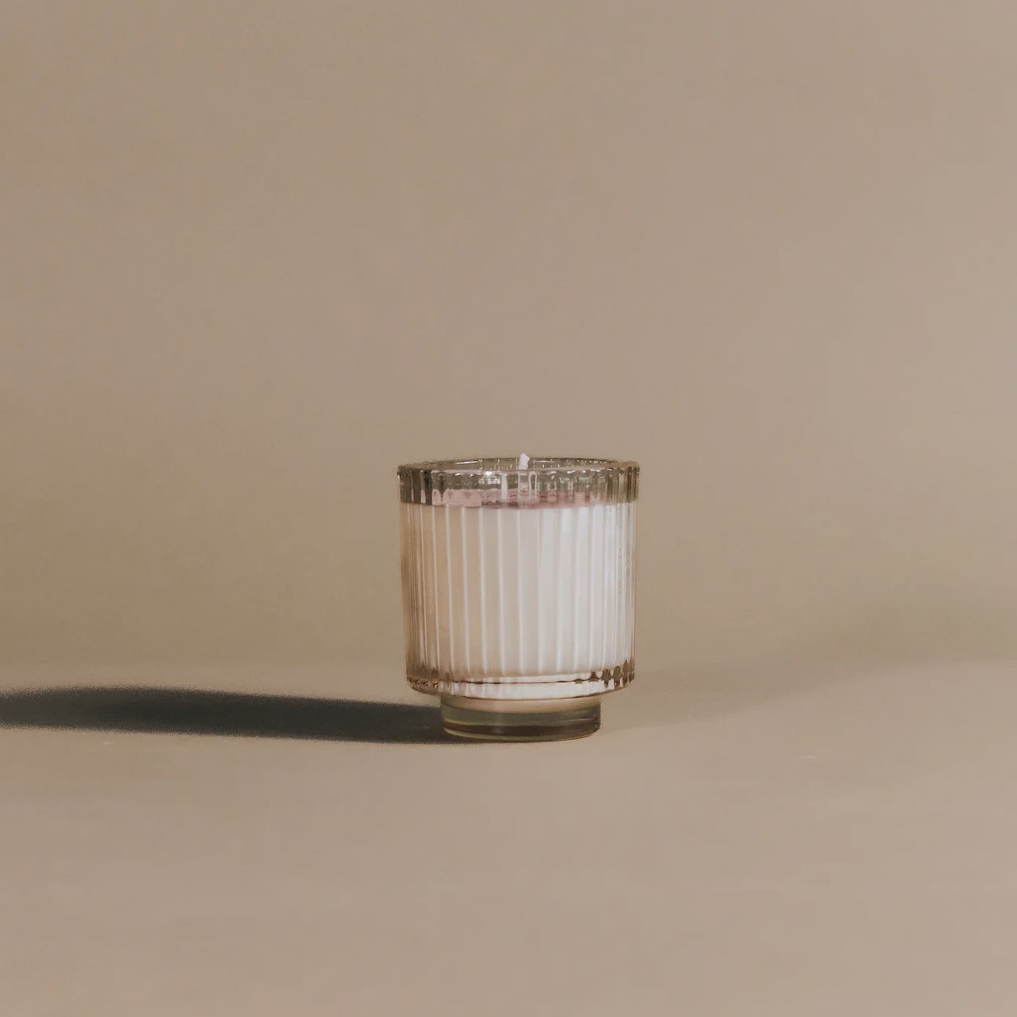 Candle in a glass holder on a beige background