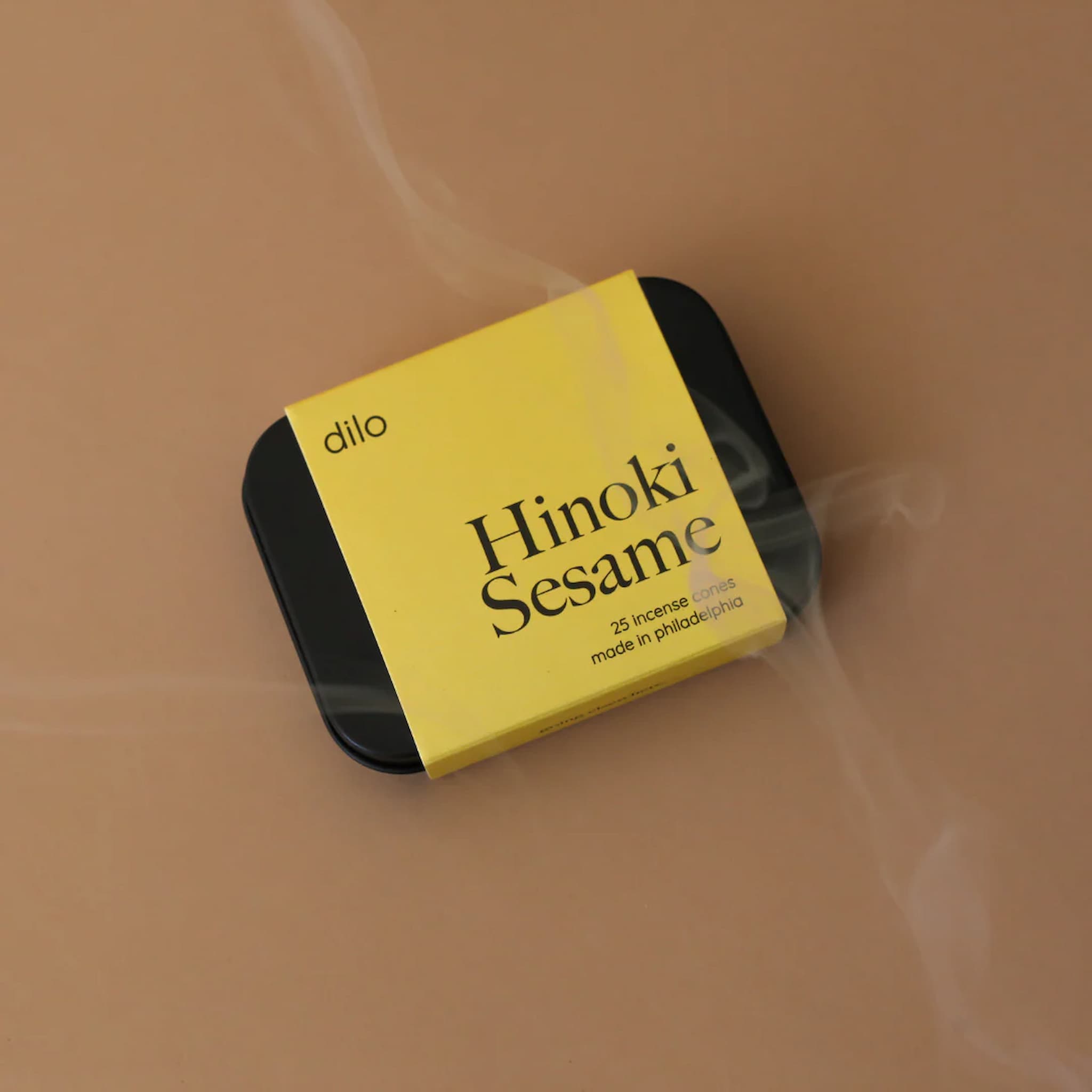 Yellow and black packaging of 'Hinoki Sesame' incense sticks by 'dilo' on a beige background.