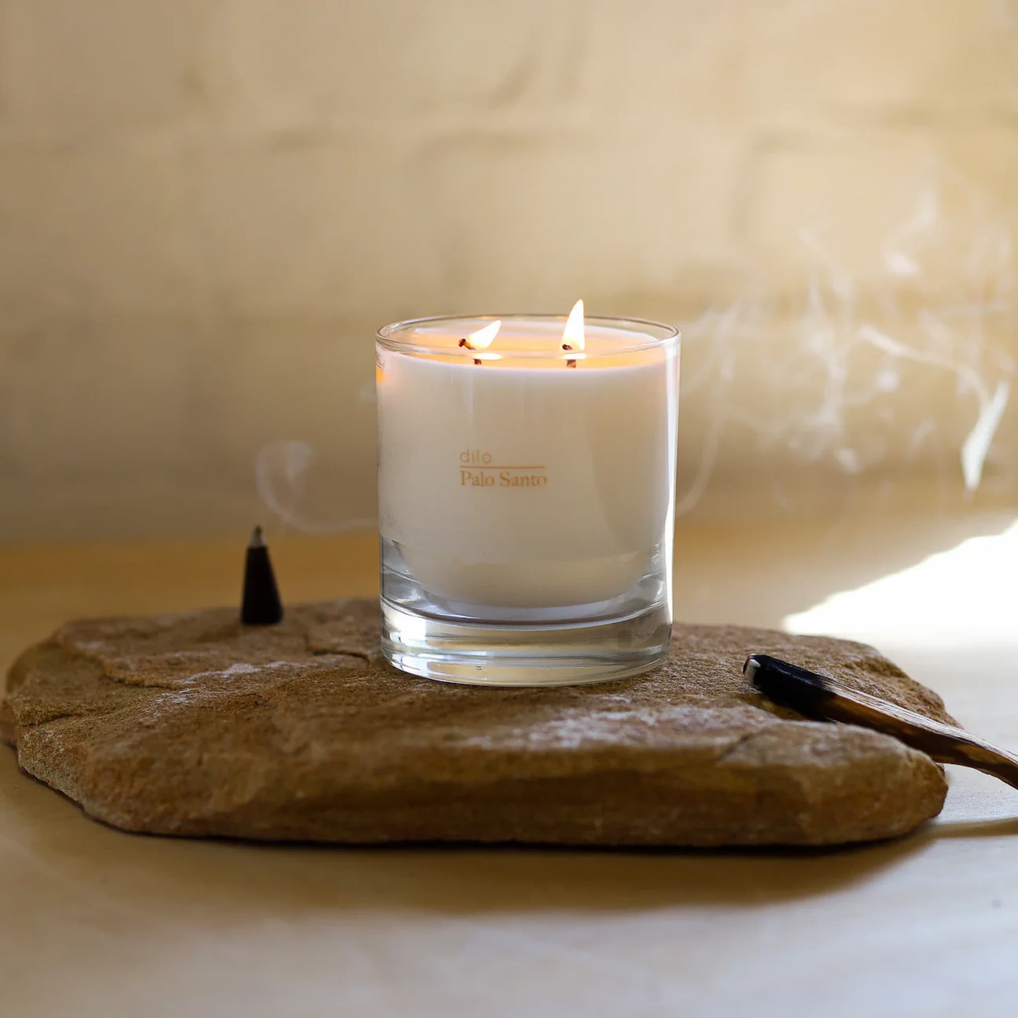 Dilo Palo Santo candle in a glass holder on a stone surface with a soft background
