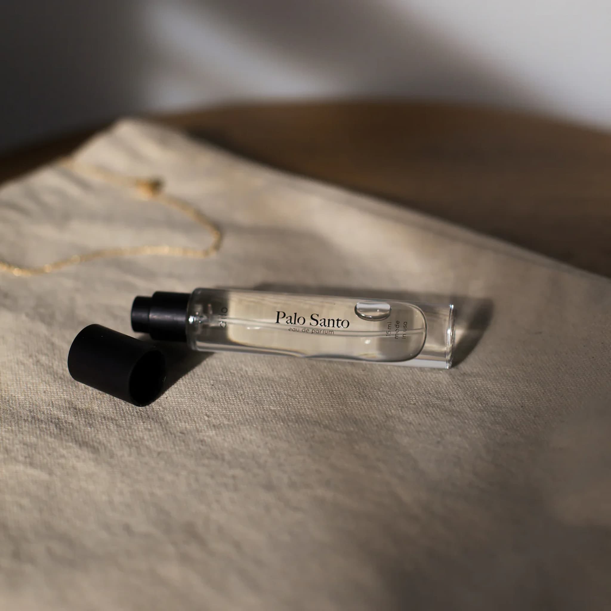 Small Dilo perfume glass bottle labeled 'Palo Santo' on a textured surface
