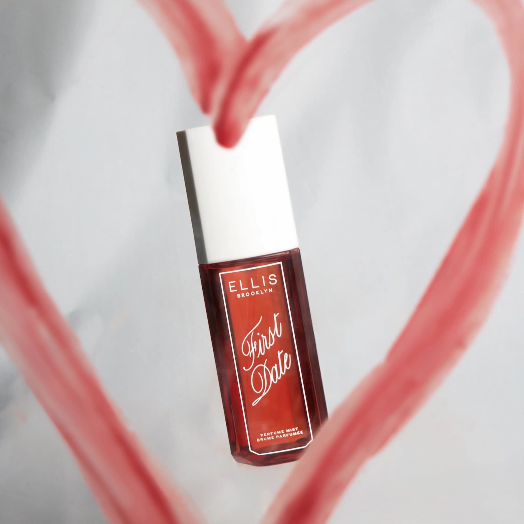 Ellis Brooklyn First Date Perfume Mist on a gray background inside a lipstick heart. 