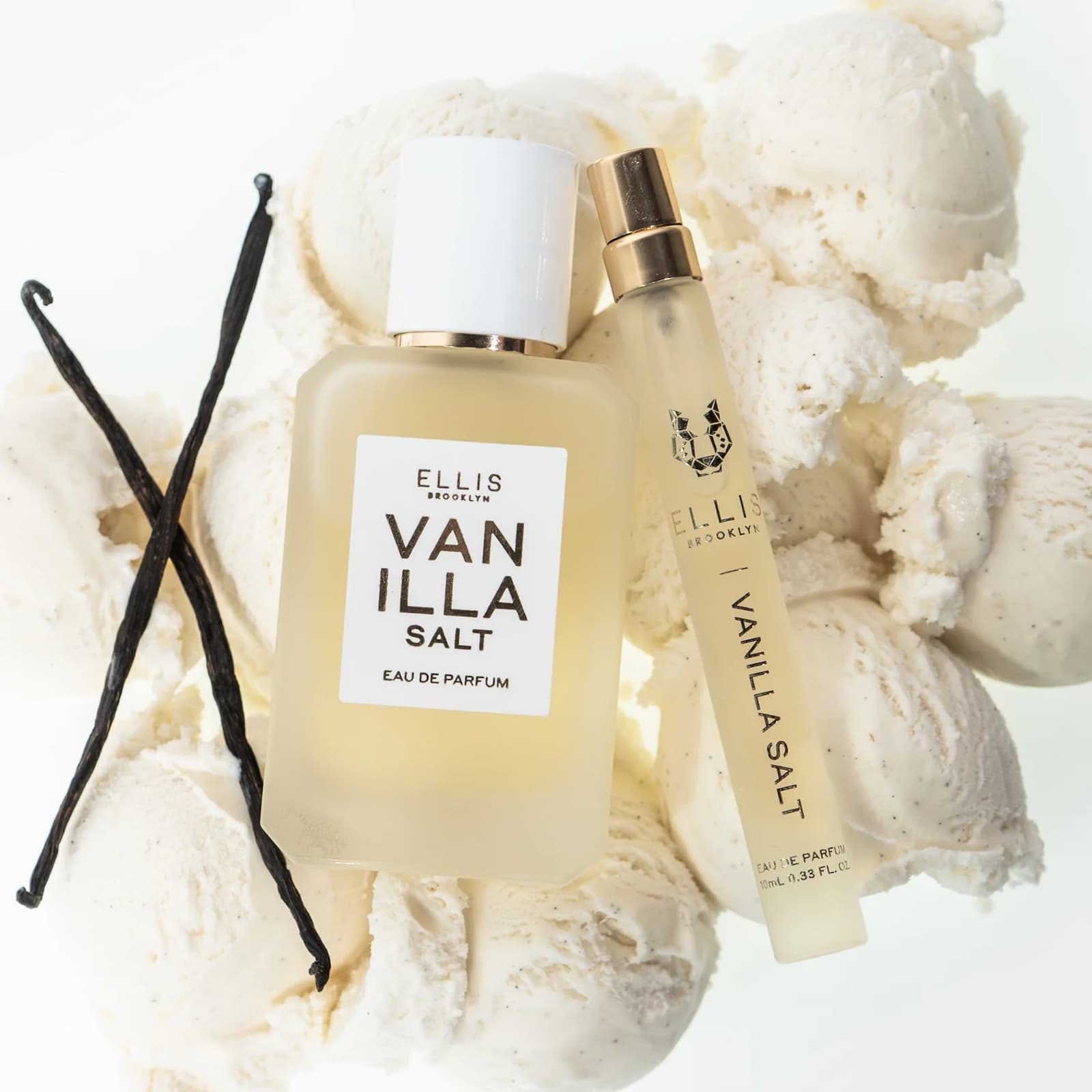 Two glass bottles of Ellis Brooklyn Vanilla Salt perfume sitting on scoops of vanilla ice cream, next to vanilla beans.