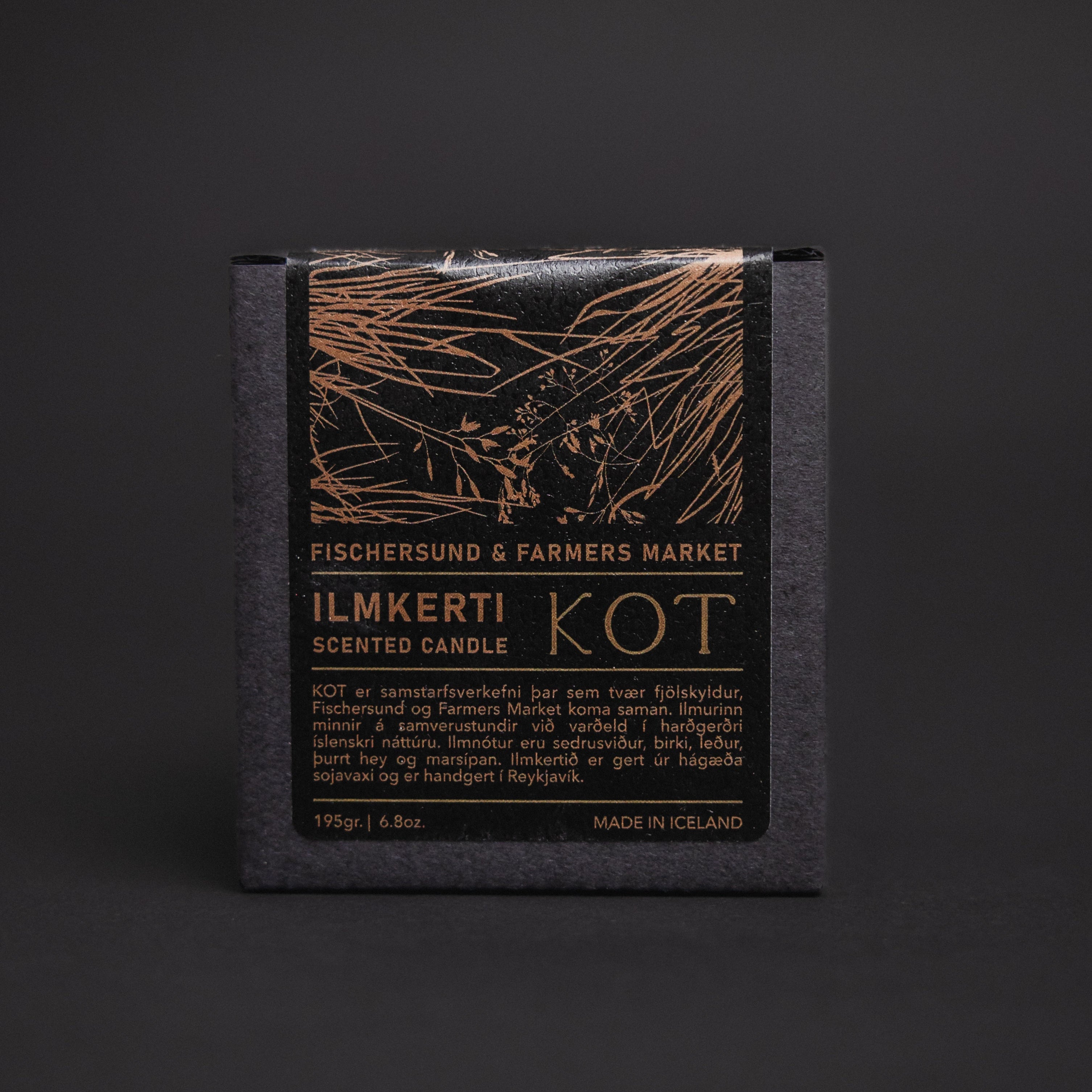 A square black Fischersund KOT candle box with a black front label featuring gold text and a gold line drawing, photographed against a dark charcoal background. Visible text includes 'FISCHERSUND & FARMERS MARKET', 'ILMKERTI', and 'KOT'.