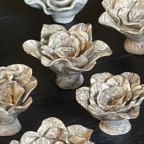 Several nerikomi rose incense holders on a dark tabletop.