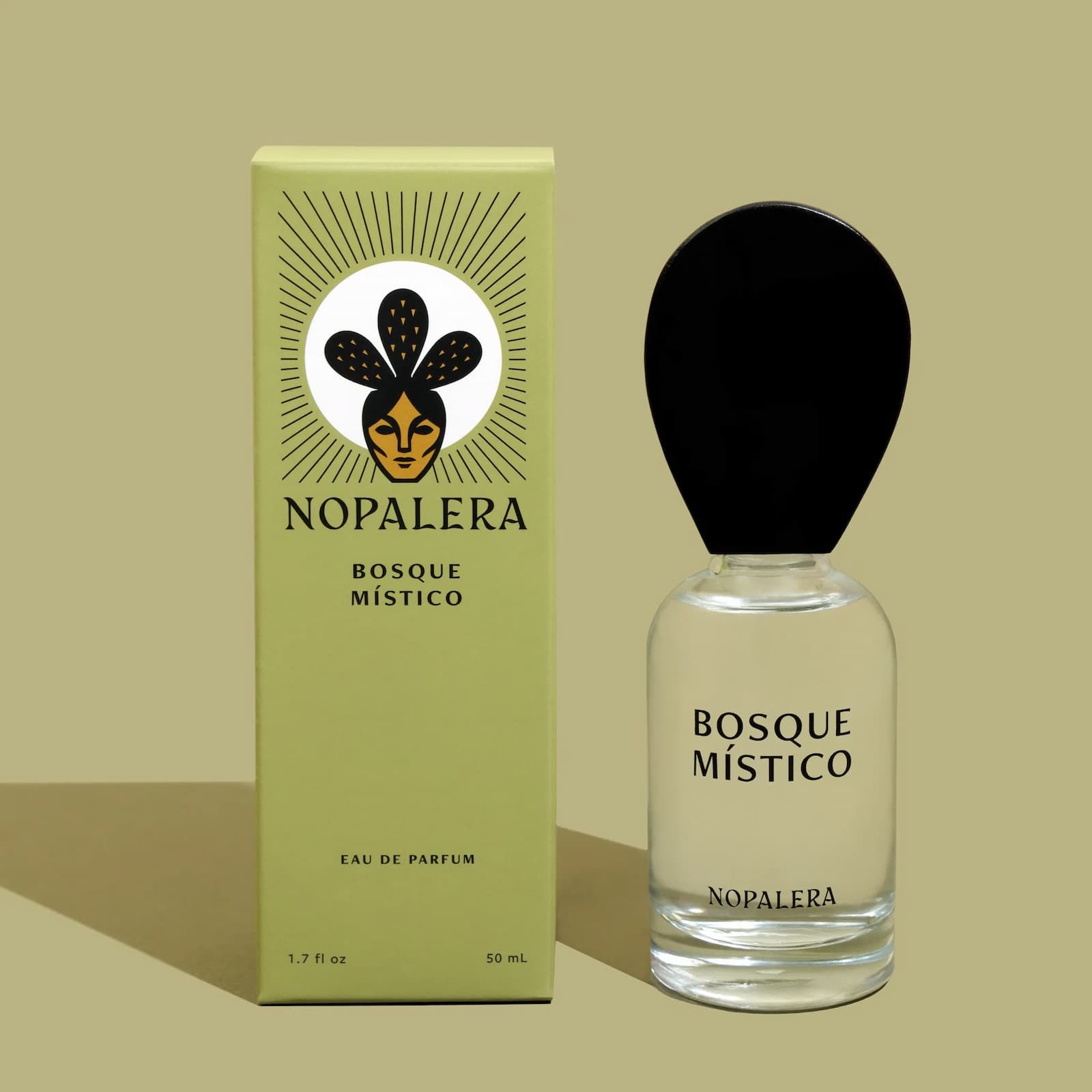 A glass bottle of Nopalera "Basque Mistico" perfume next to its green packaging box against a lighter green background.