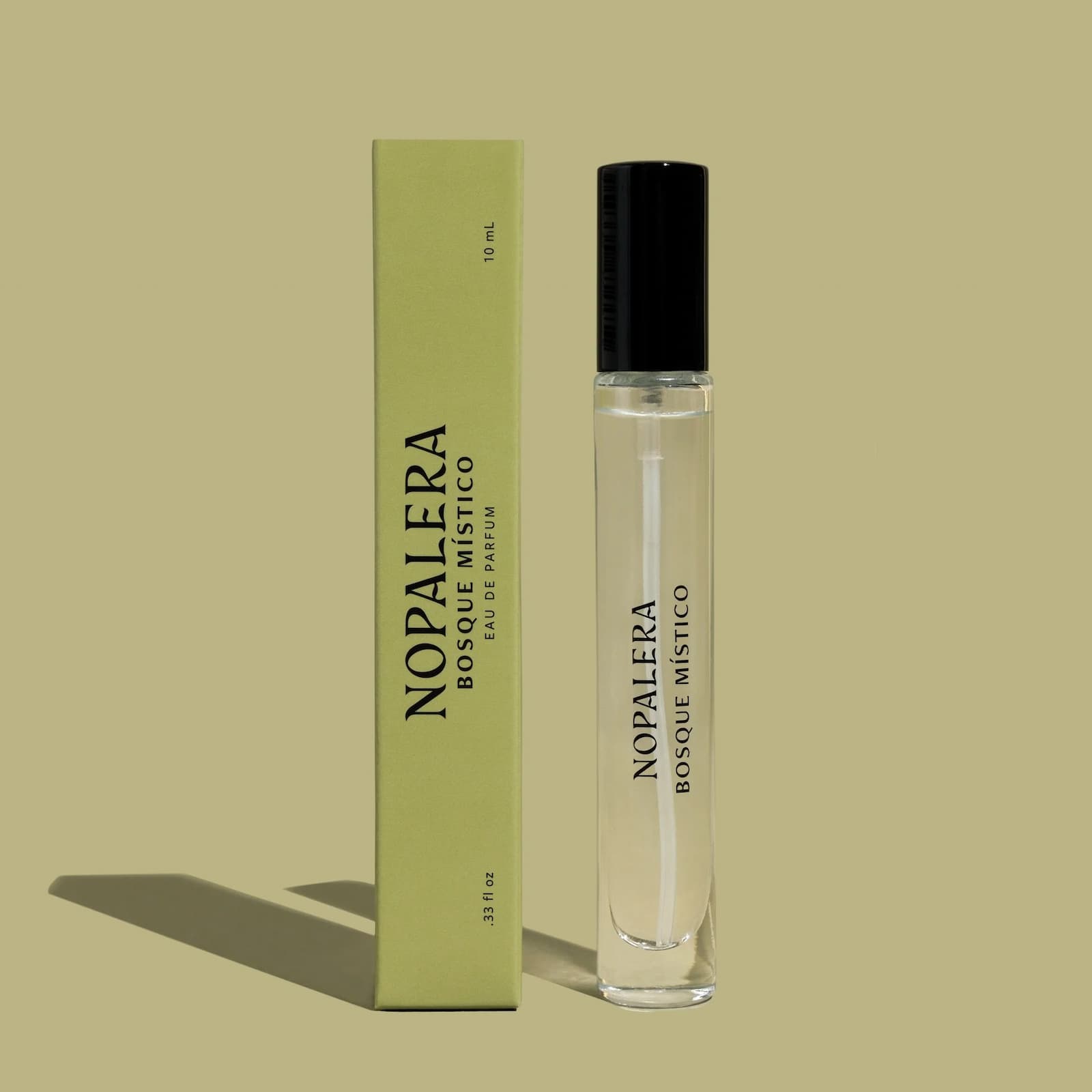 A slim, travel-sized glass bottle of Nopalera "Basque Mistico" perfume next to its green packaging box, against a lighter green background.