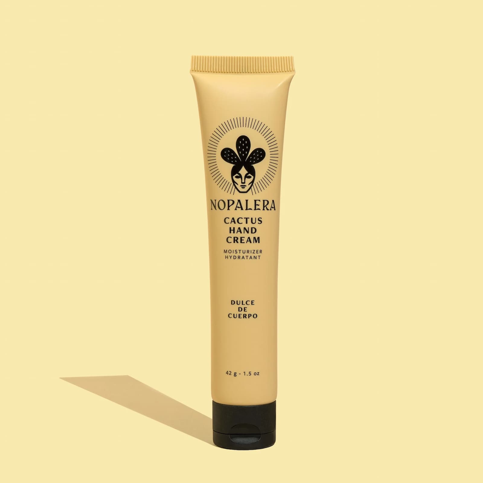 A yellow squeeze tube of Nopalera Cactus Hand Cream in "Dulce de Cuerpo" against a yellow background.