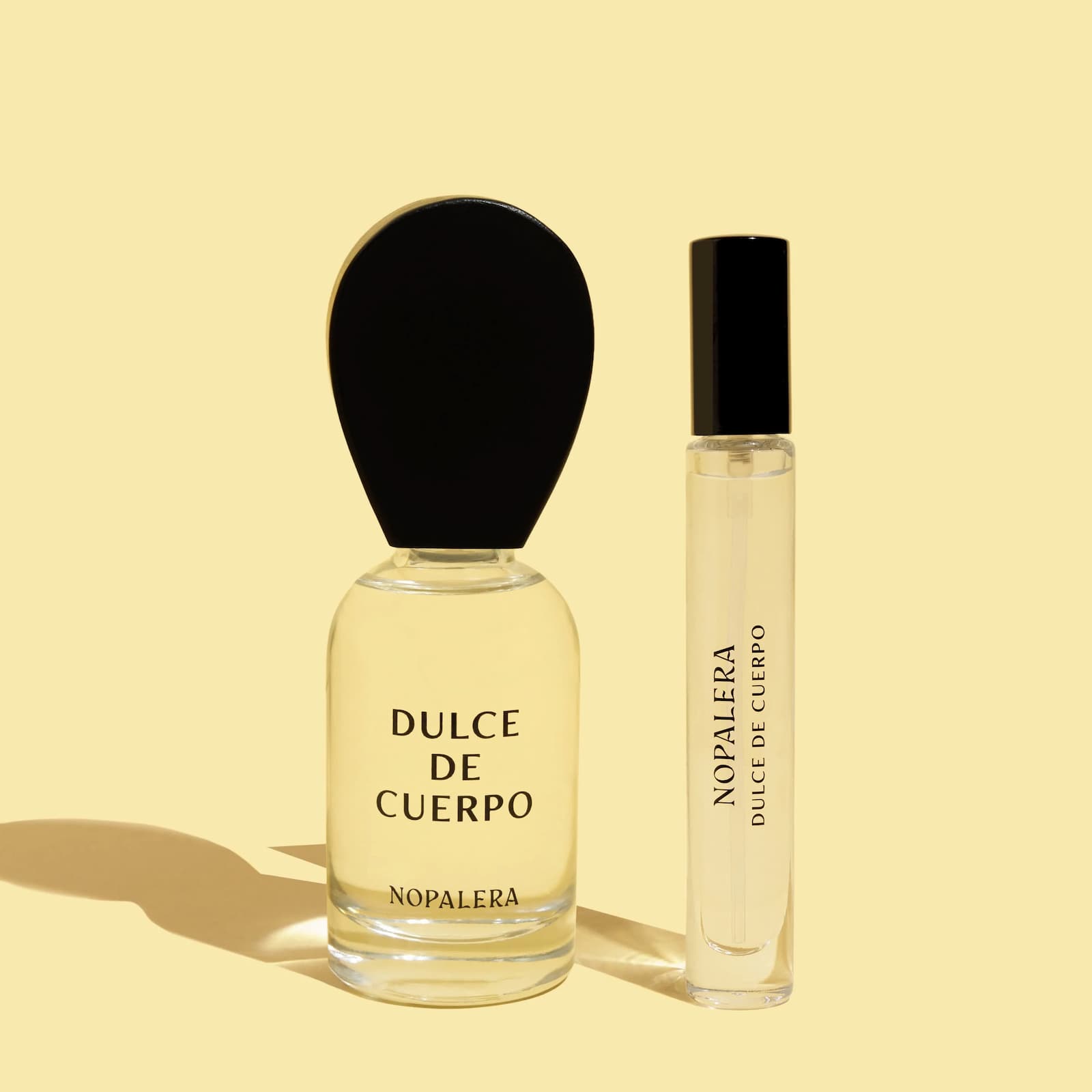Two glass bottles of Nopalera Dulce de Cuerpo- one 50ml, the other 10ml- side by side on a yellow background.