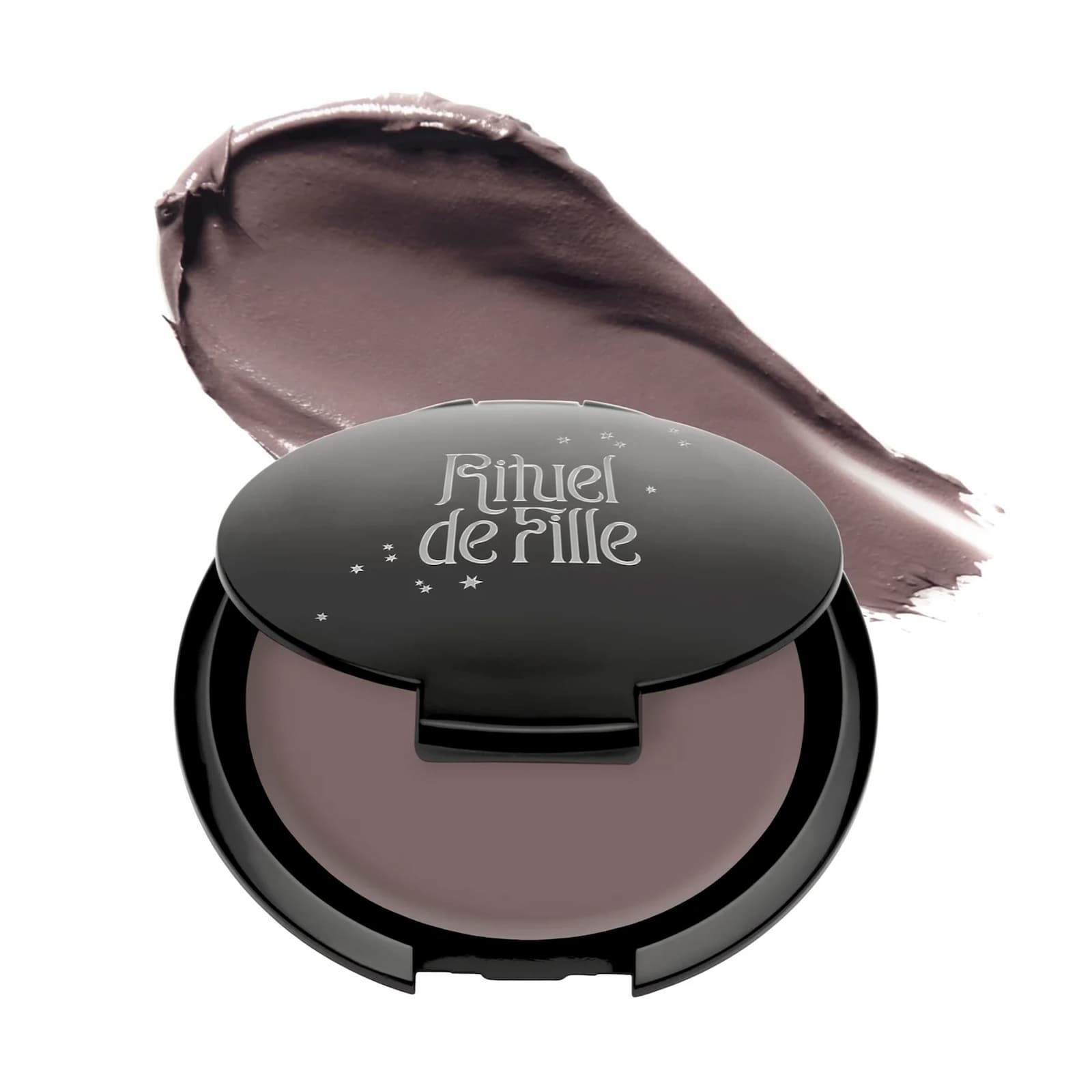 A black makeup compact with a swatch of product behind it against a white background. Rituel de Fille Inner Glow Creme Pigment in "Intuition".