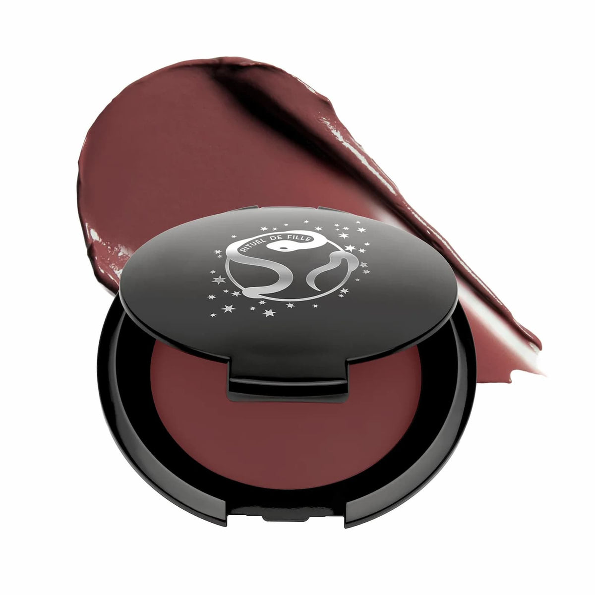 A black makeup compact of Rituel de Fille Inner Glow Pigment Balm in "Moth", with a swatch of product behind it.