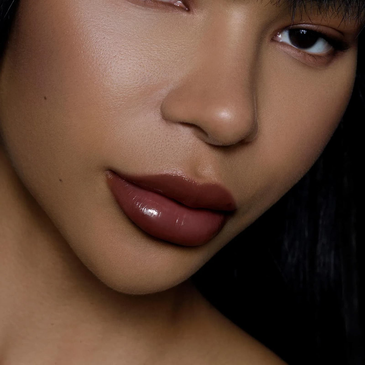 A close-up of a model's face. They are wearing Rituel de Fille Inner Glow Pigment Balm in "Weeping Cherry".