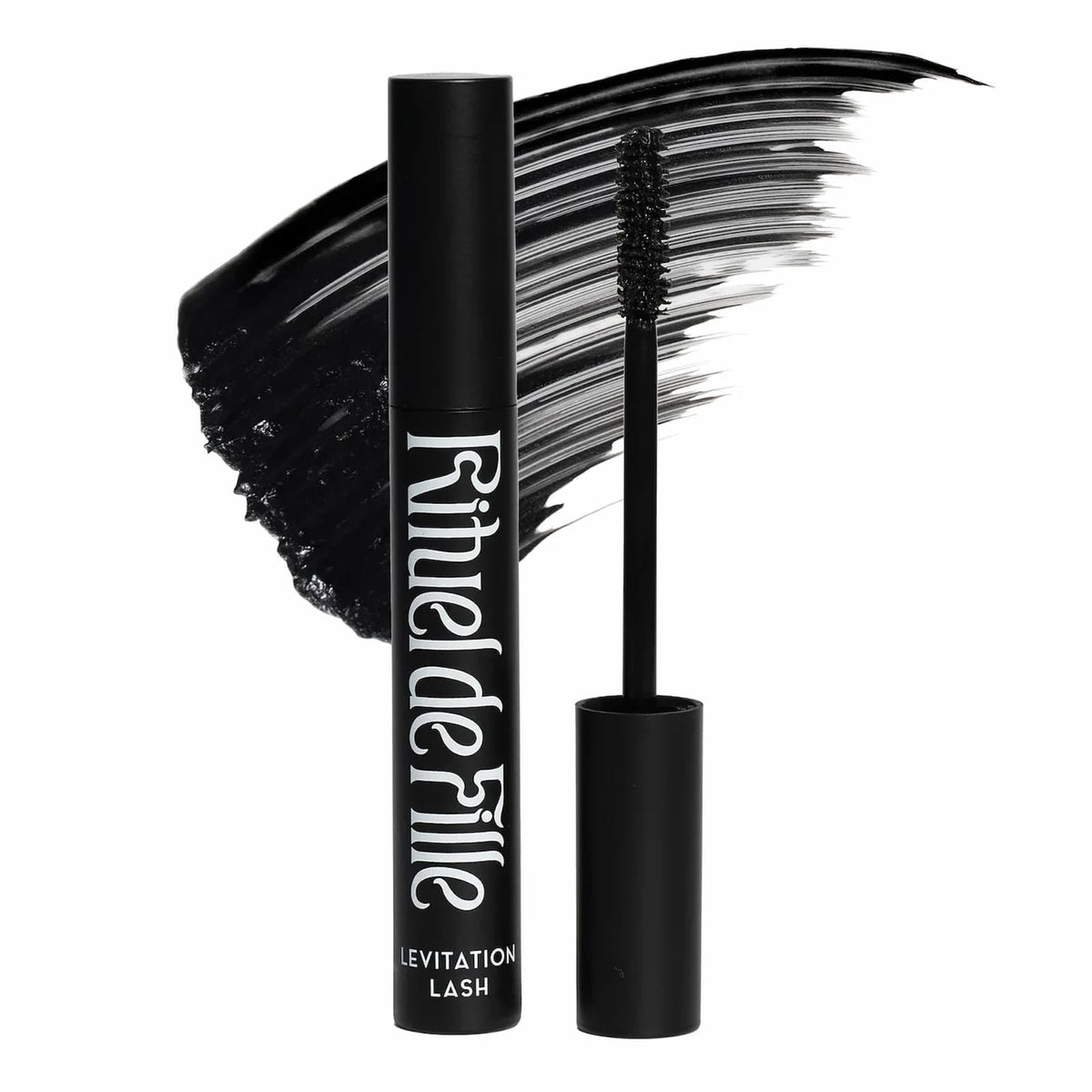A black tube of Rituel de Dille Levitation Lash mascara next to the mascara wand, with a black smear of product behind it. The image is on a white background.