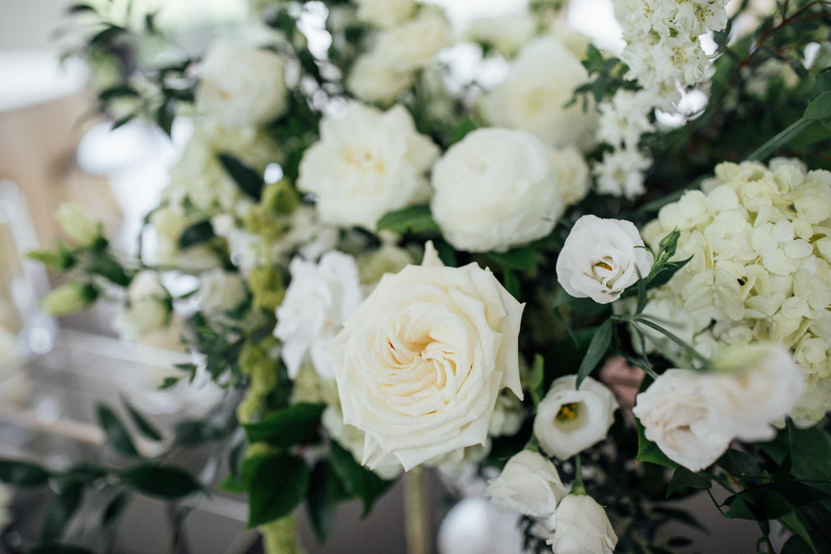 A close-up of a wedding floral arrangement by Witch Hazel featuring white roses, white hydrangeas, and green foliage. Shown at the Roundhouse in Beacon, NY.