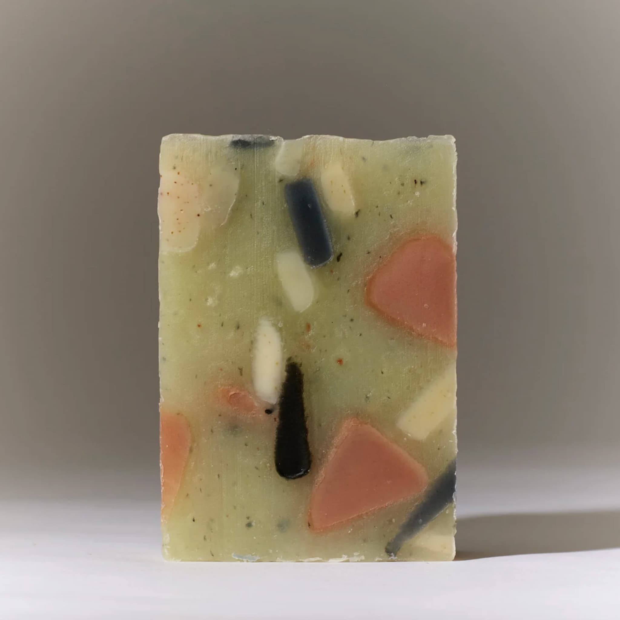 Rectangular bar of soap with colorful embedded pieces on a neutral background